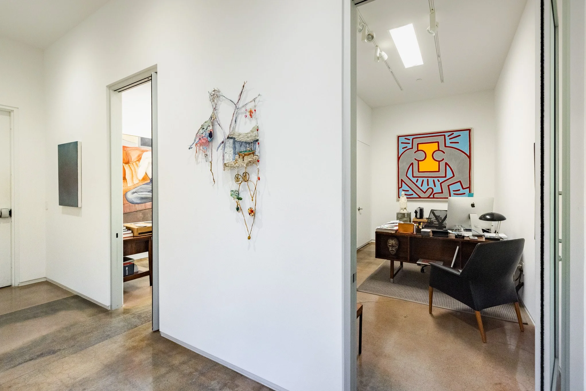 Office space with modern decor, artwork, and a desk with a computer and chair.