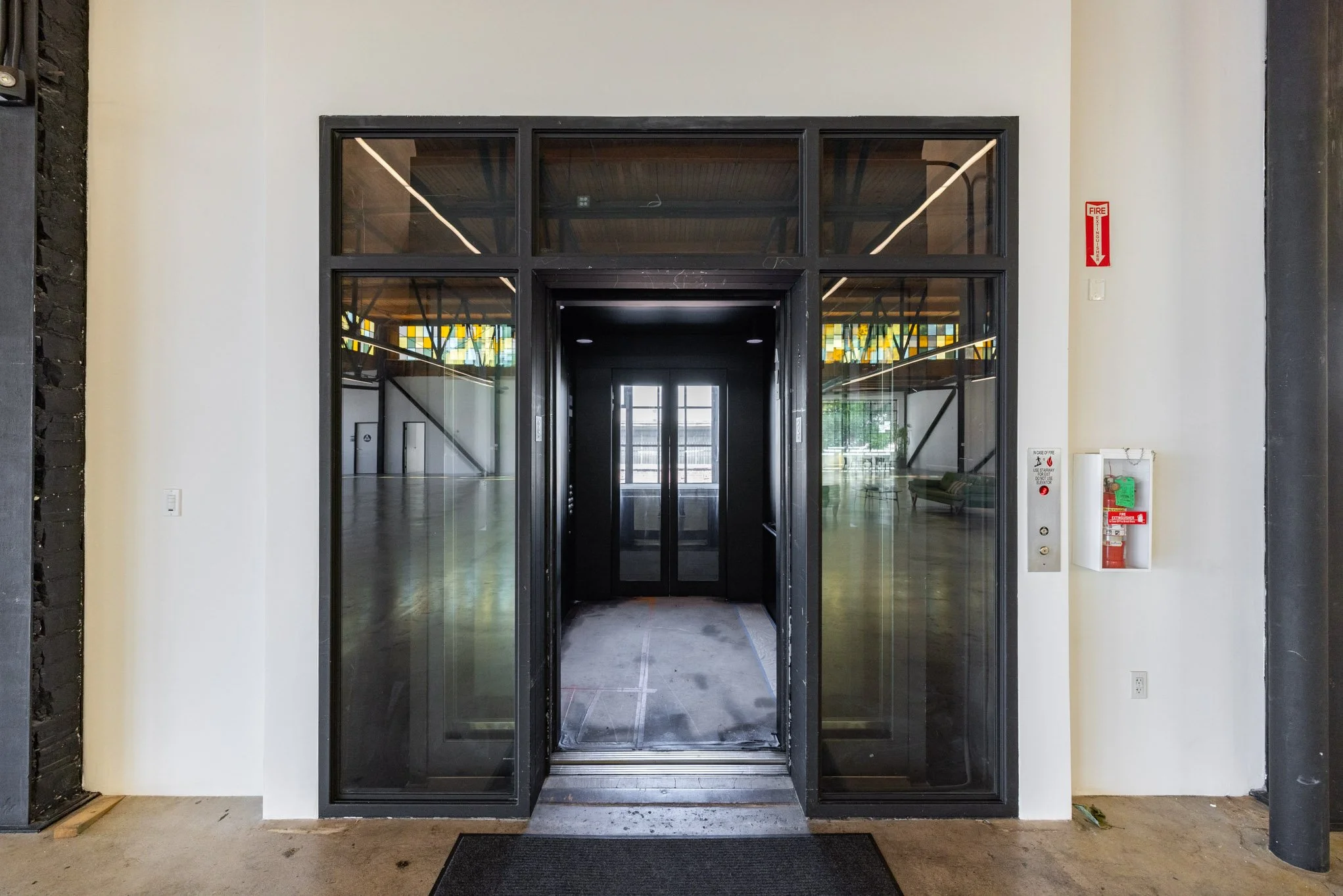 Elevator doors with glass panels in a modern building lobby.