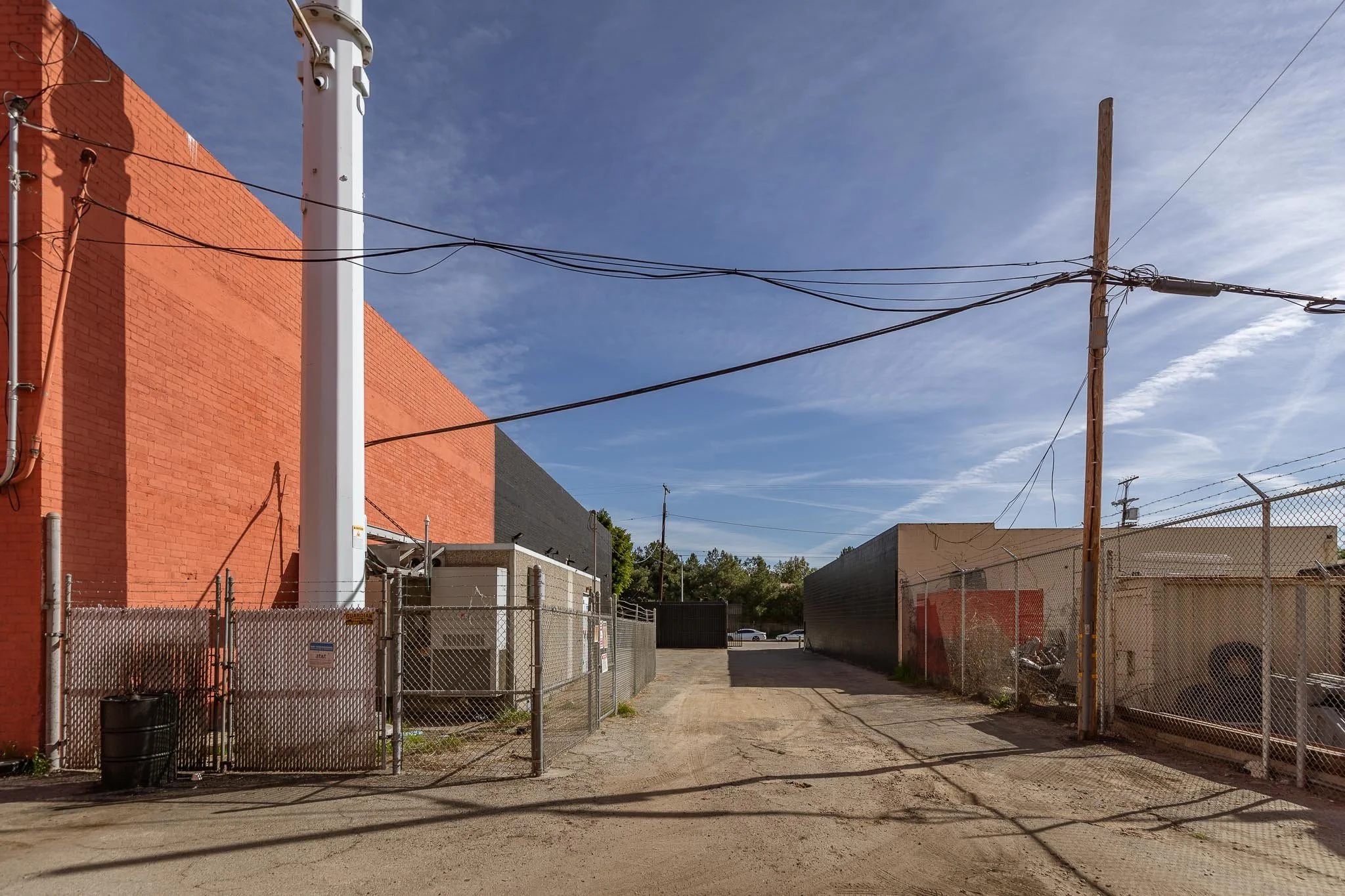 Back alley with fences, utility poles, and a clear sky.