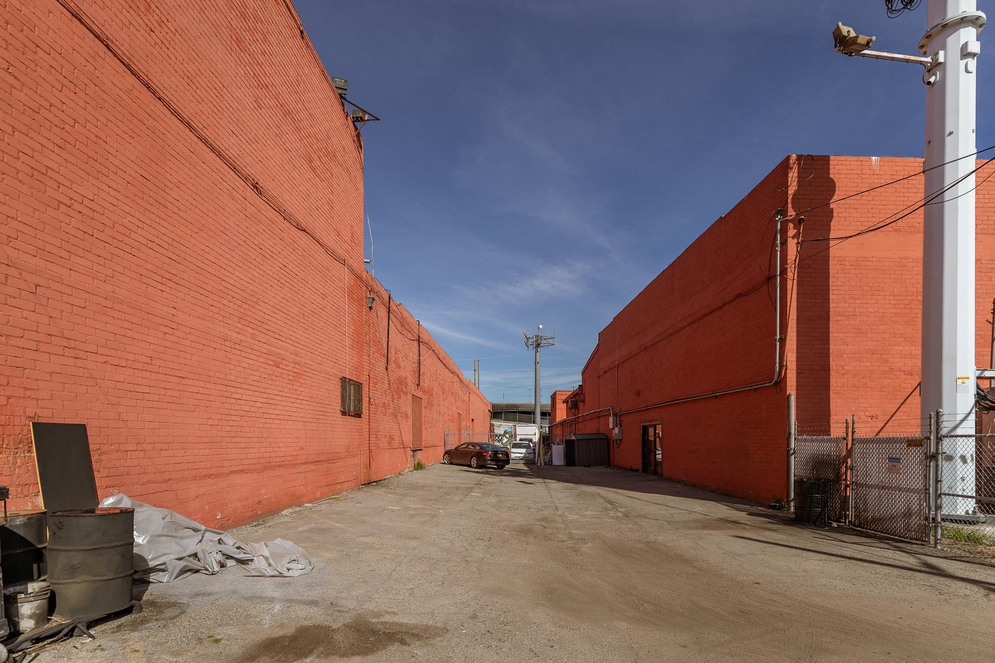 An alleyway between two large red brick buildings under a clear blue sky.