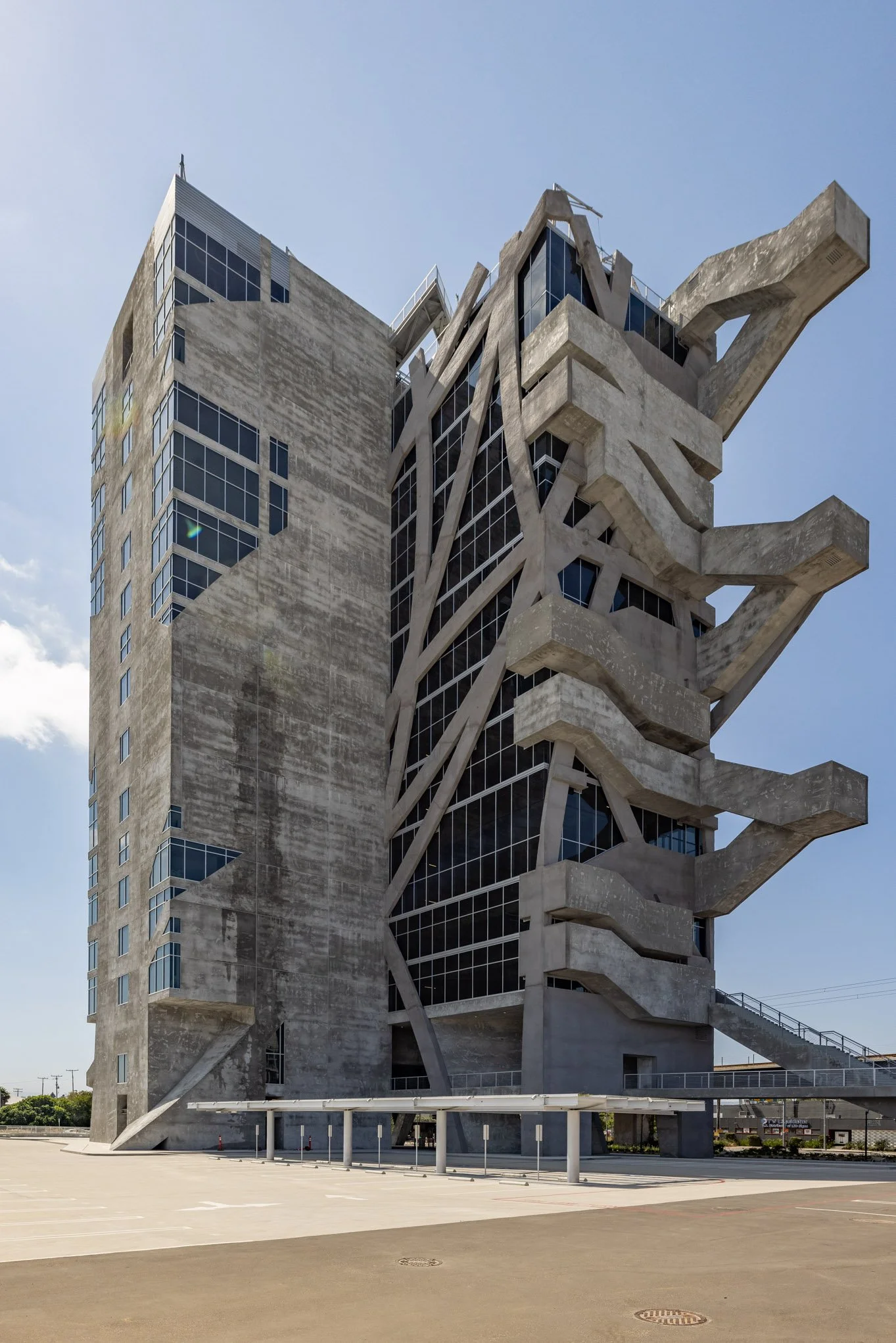 A modern concrete and glass building with industrial, tree-like structures extending from the sides and upper levels.