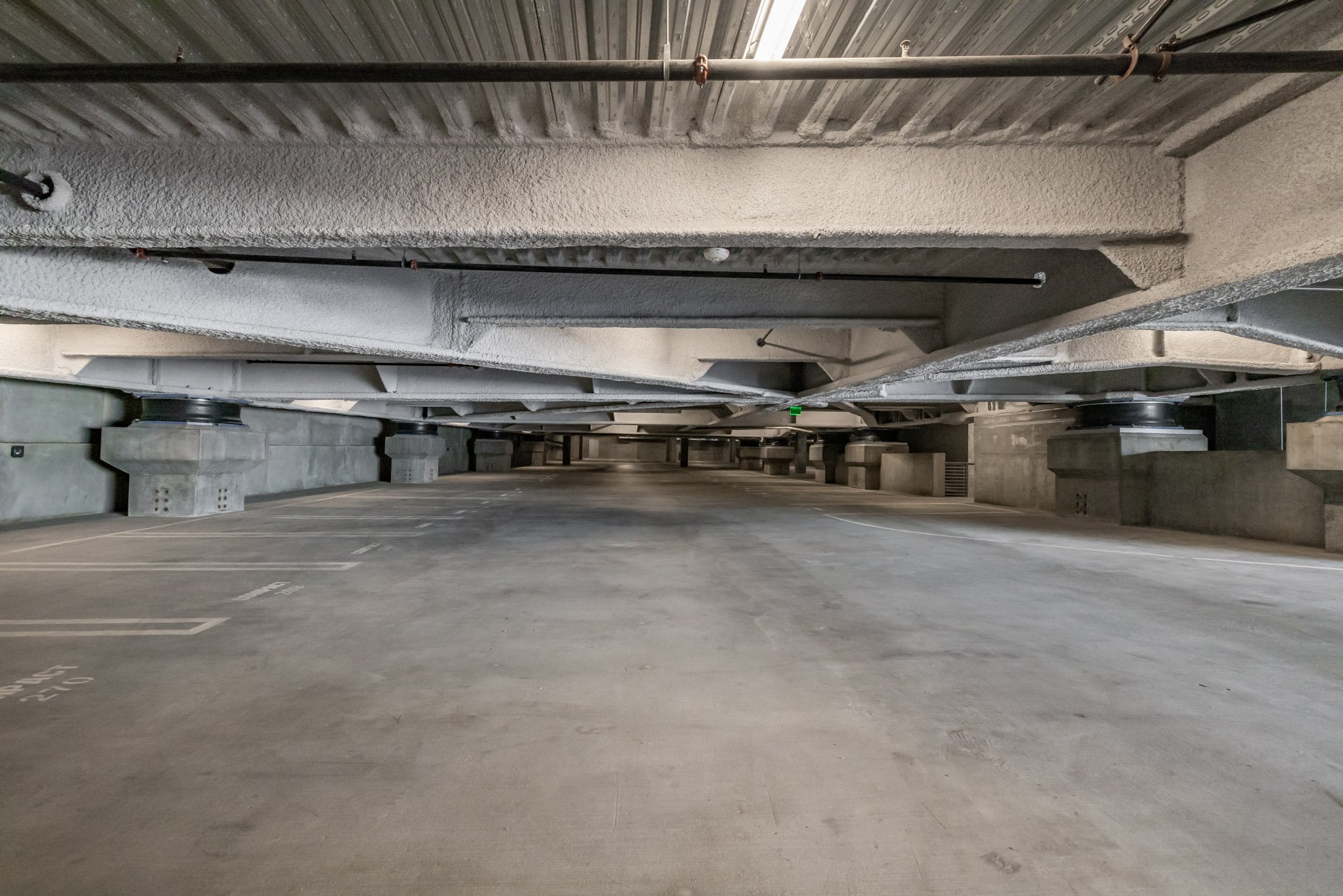 Underground parking garage with a concrete ceiling, supporting columns, and empty parking spaces.