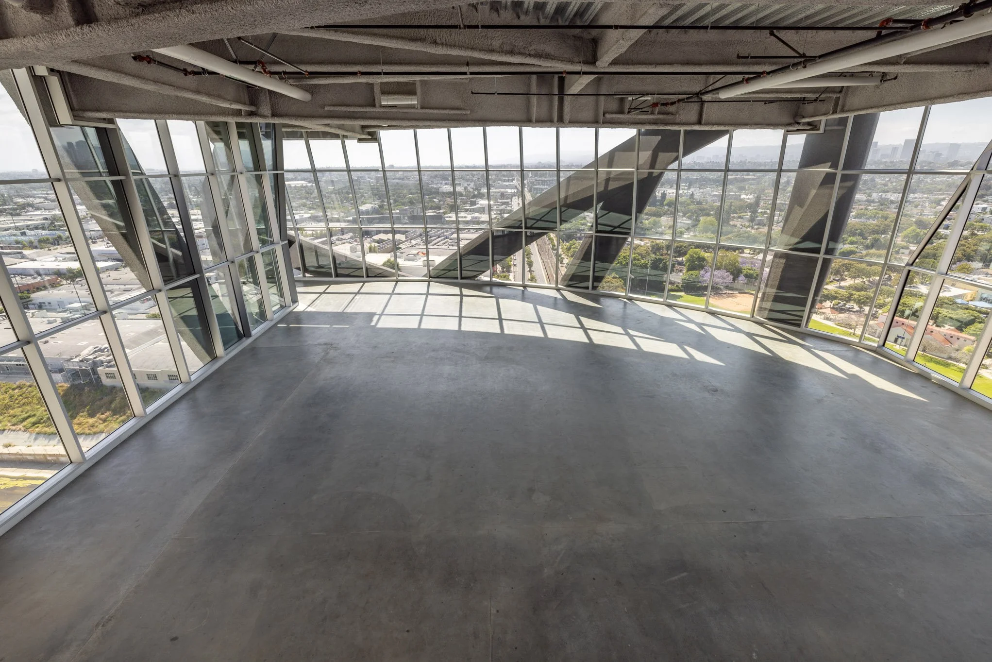 Empty room with large floor-to-ceiling windows and a view of the cityscape.