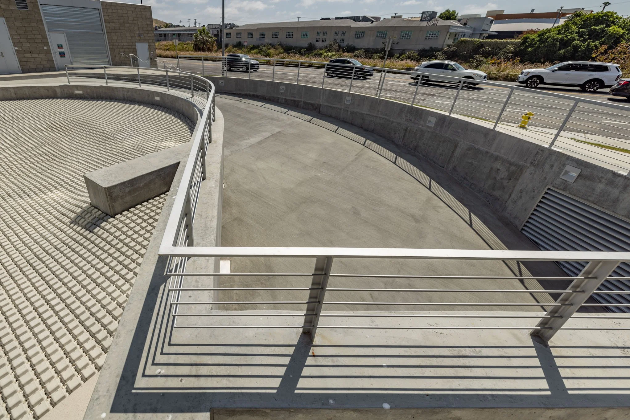Empty outdoor balcony with metal railing, concrete floor, and street with cars in the background.