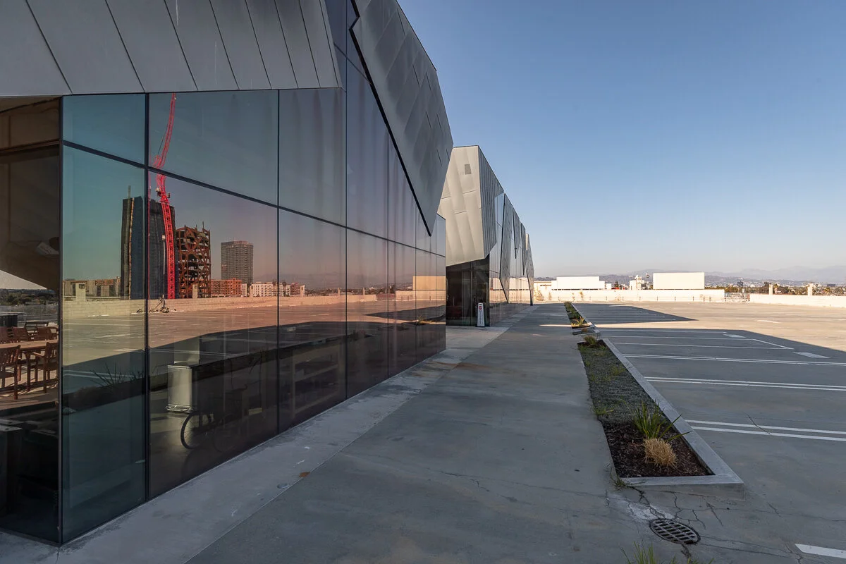 Empty rooftop parking lot and modern building with reflective glass walls.