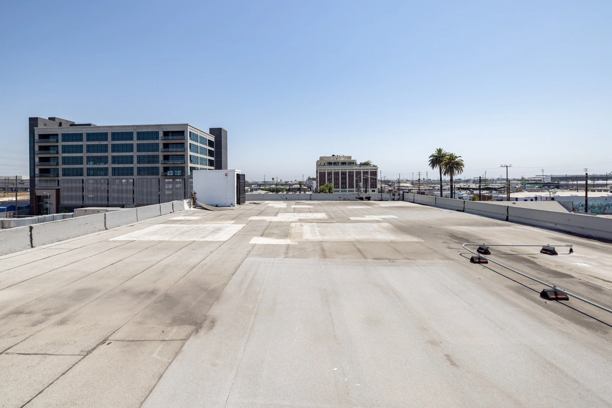 Empty rooftop with rooftop lights and cityscape in the background, clear blue sky.