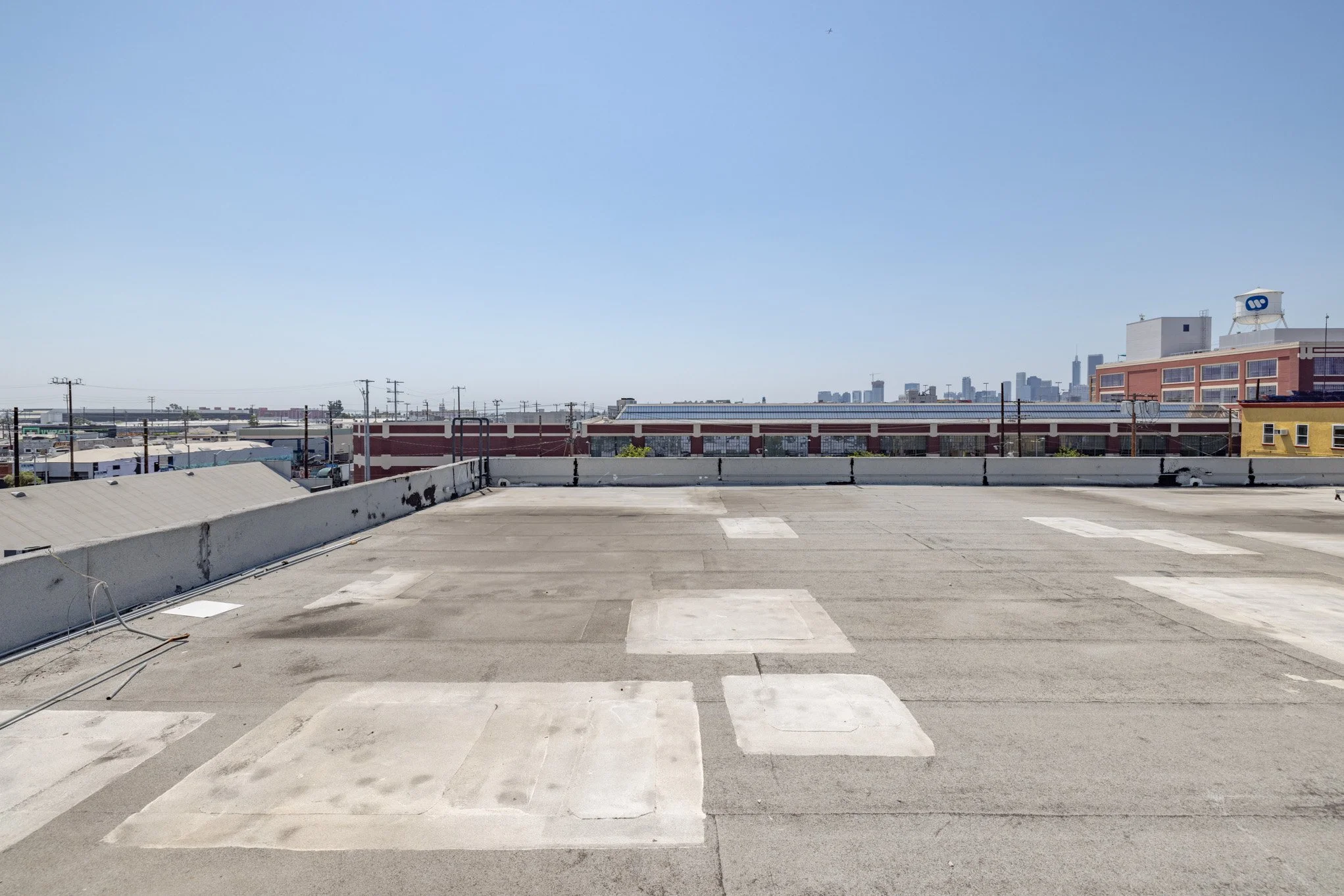Empty rooftop parking lot with city skyline in the distance under a clear blue sky.