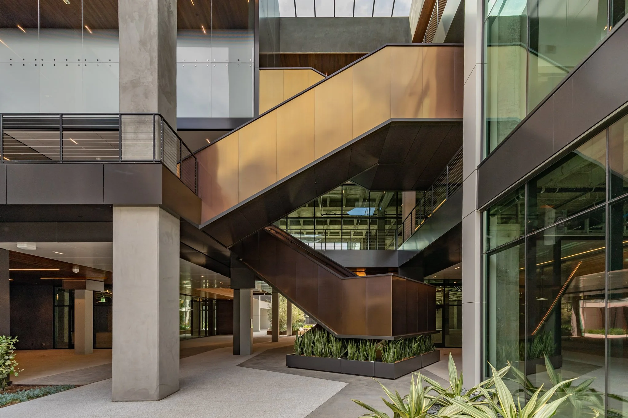 Modern multi-story office building interior with open staircase and glass walls.