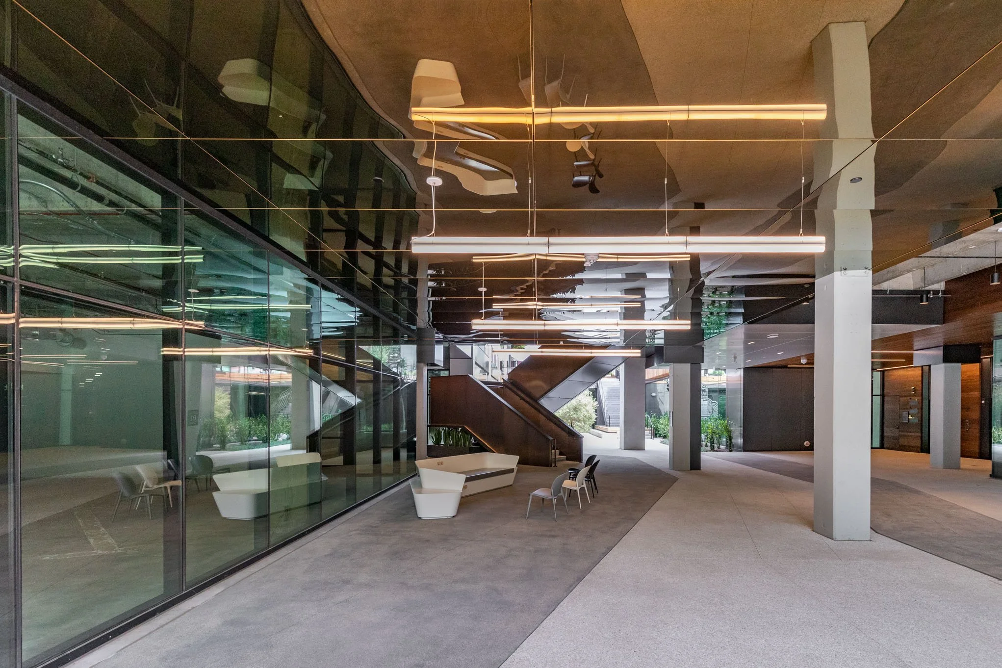 Modern office lobby with glass walls, contemporary furniture, and ceiling lighting fixtures.