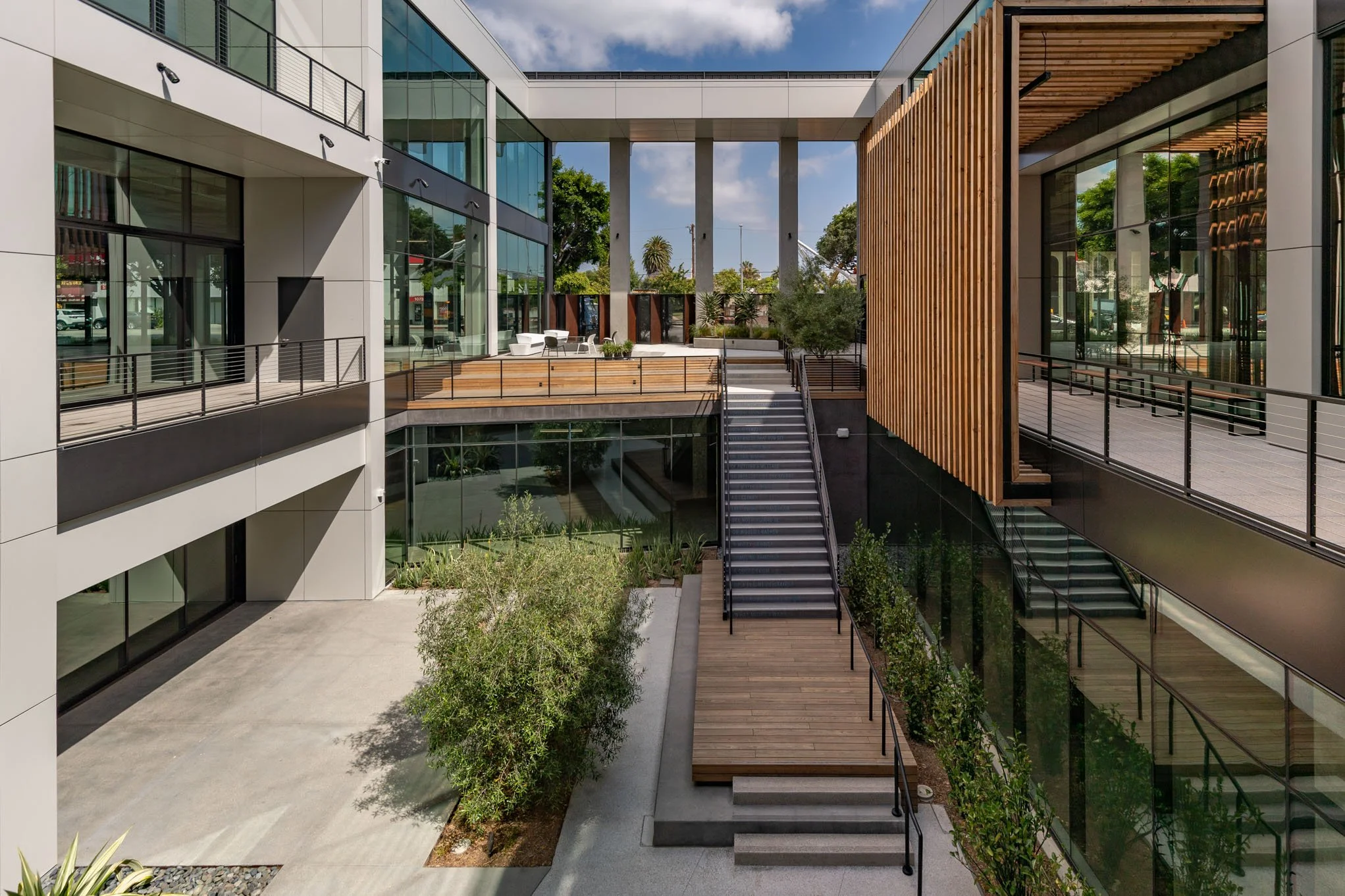 Modern multi-story building with glass windows, outdoor stairs, and landscaped seating area.