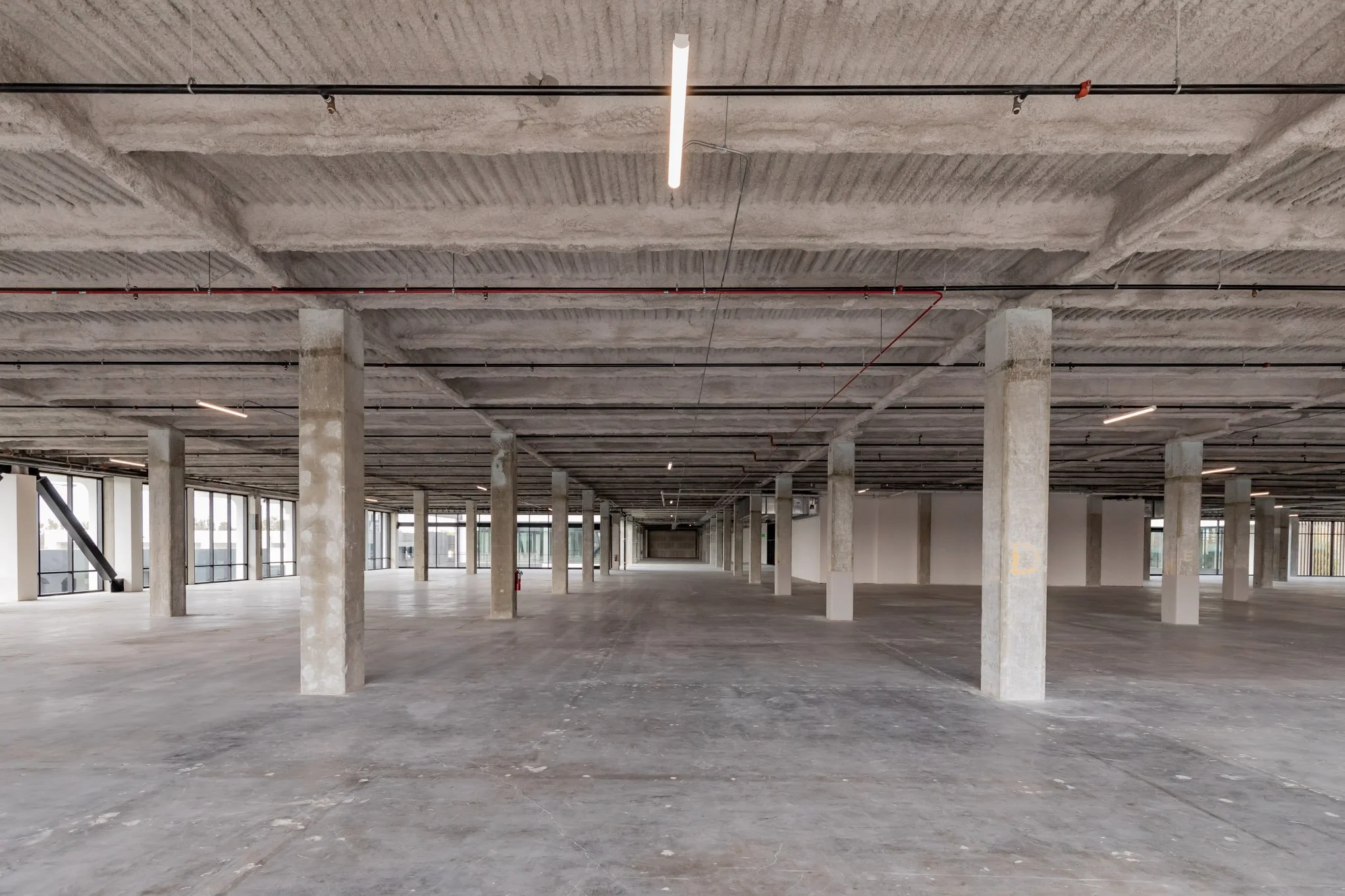 Empty multi-story parking garage with concrete pillars and large windows along the side walls.