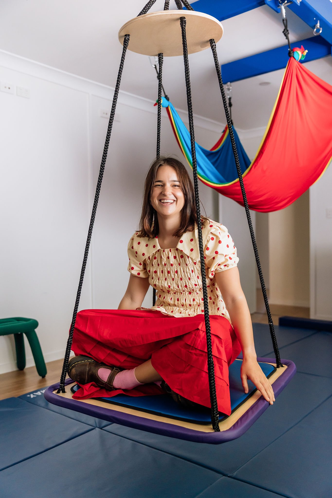 Jo, founder of Grow together OT sitting on a playground swing inside occupational therapy clinic school in Buderim Queensland
