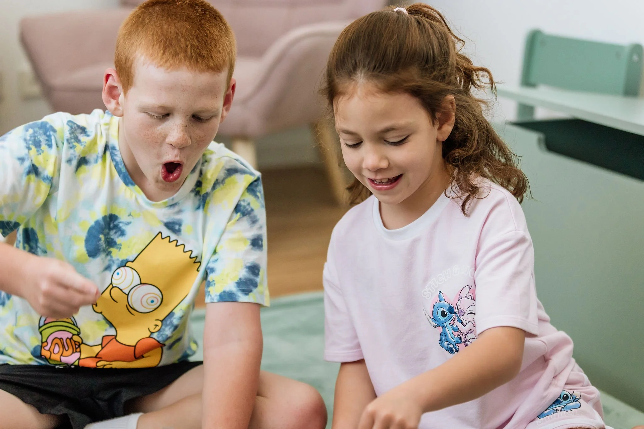 A boy and a girl sitting on the floor, playing during occupational therapy session