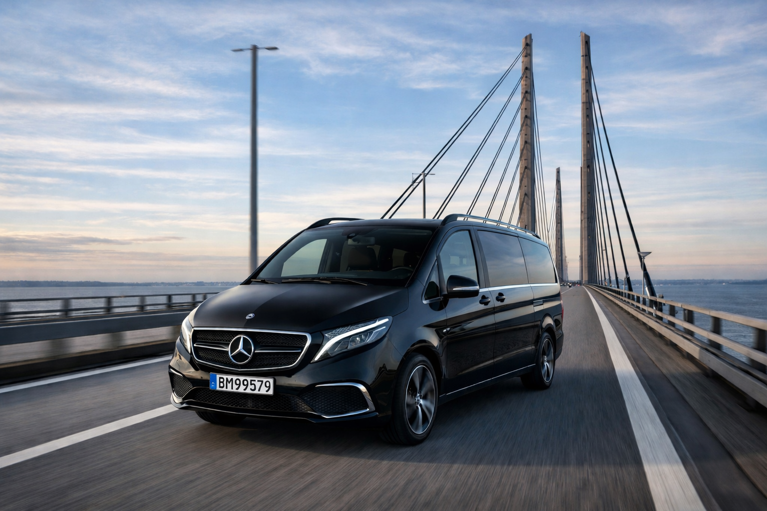 A black Mercedes-Benz van driving on a bridge over water with a clear sky above malmo ,sweden  ,copenhagen oresund bridge .