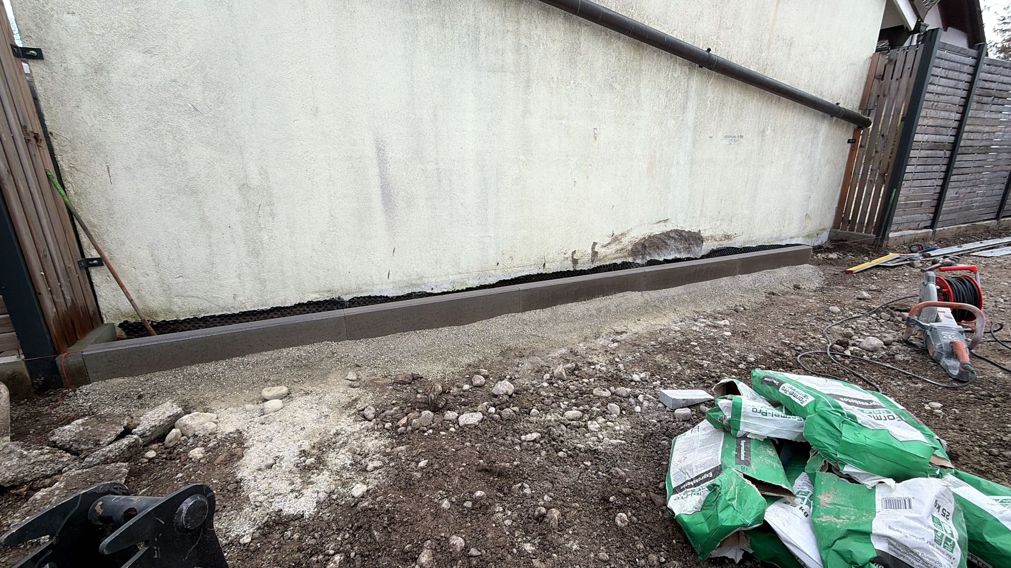 Baustelle mit Fundamentierung und Bauarbeiten im Außenbereich, Save-Maschinen, Bauutensilien, und Kies.