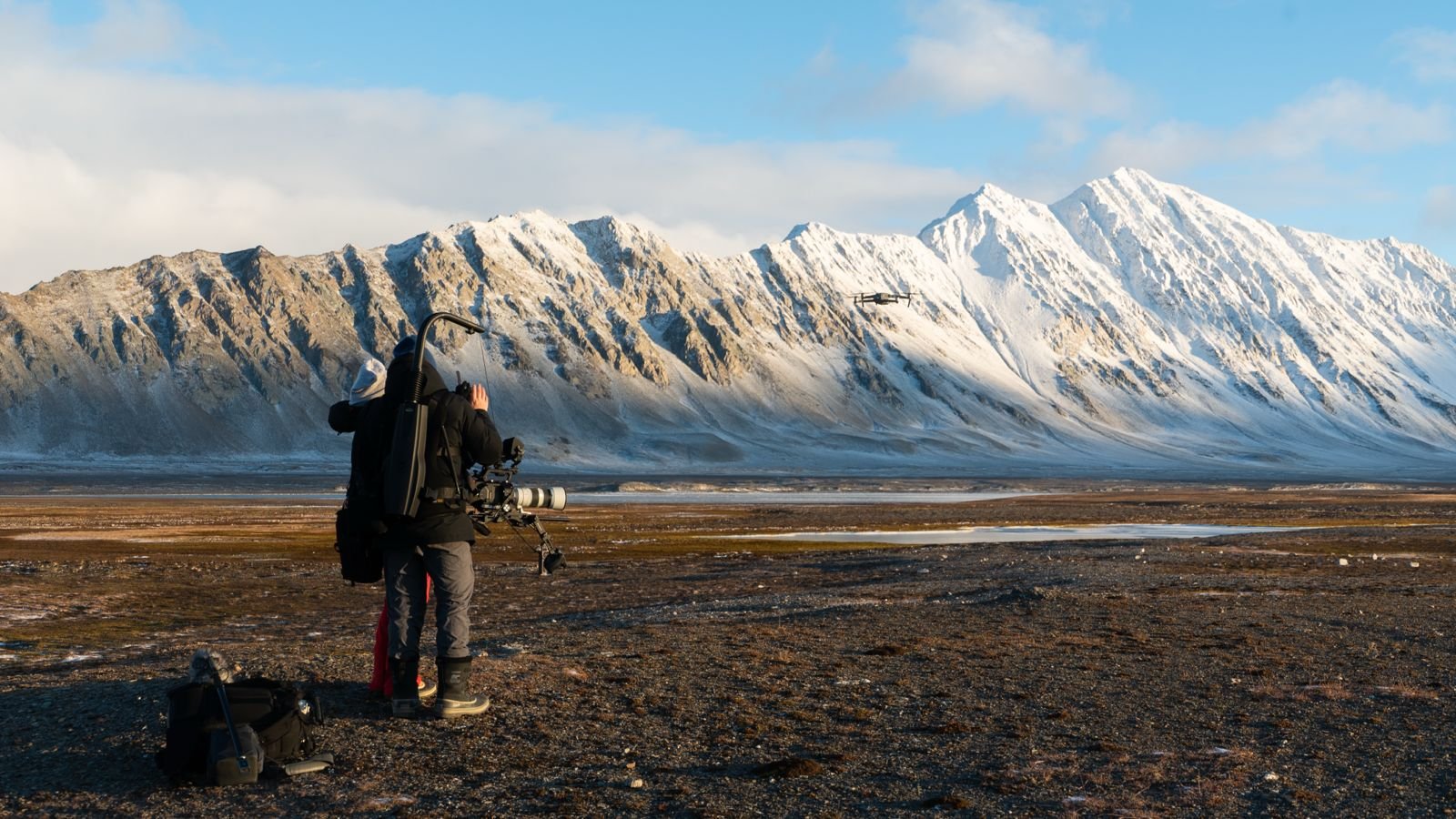 Thought Leader crew with camera gear filming snowy mountain landscape in Iceland with a drone flying nearby.