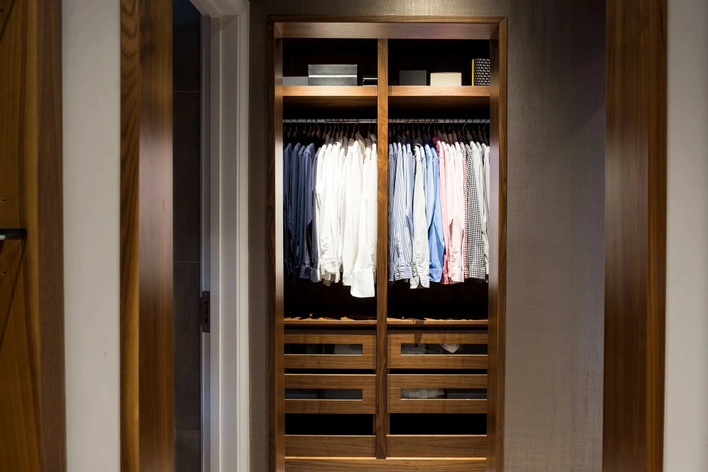 Wooden closet with neatly hung shirts and shelves.