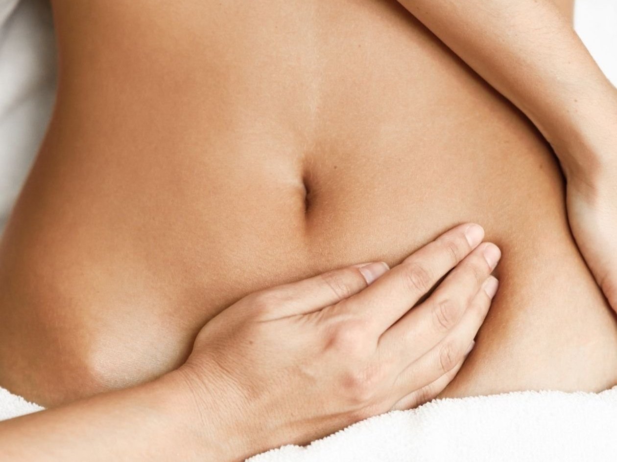 Weiblicher Bauch mit massierenden Händen