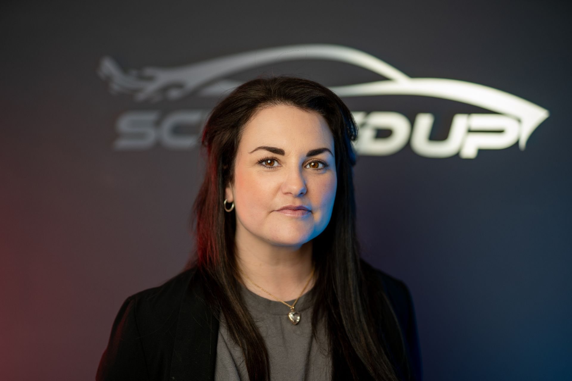 A professional woman with dark hair and hoop earrings standing in front of a dark background with the 'Scuffed Up' logo.