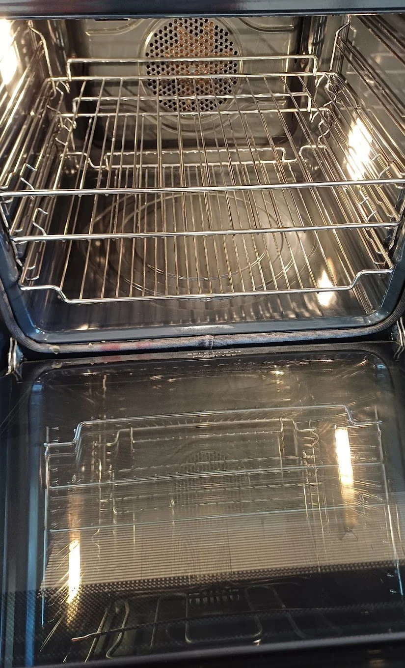 Empty stainless steel oven with two racks and a glass door.