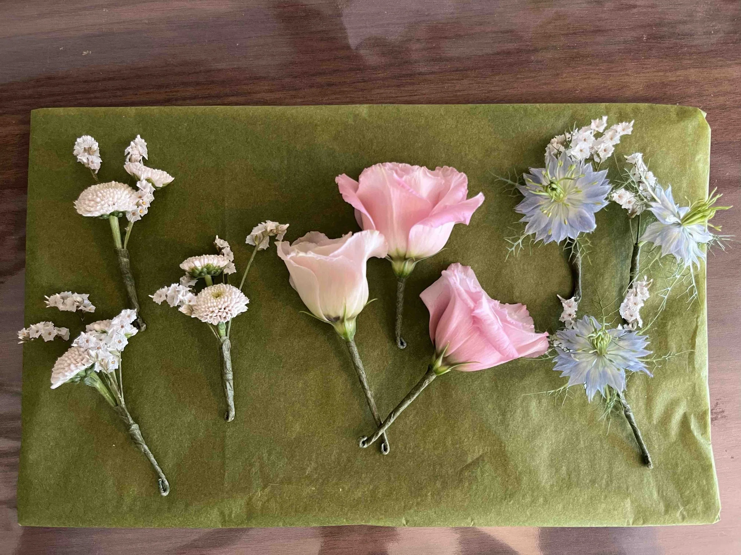 Ett arrangemang av konstgjorda blommor på ett grönt underlag, inklusive vita och rosa blommor.