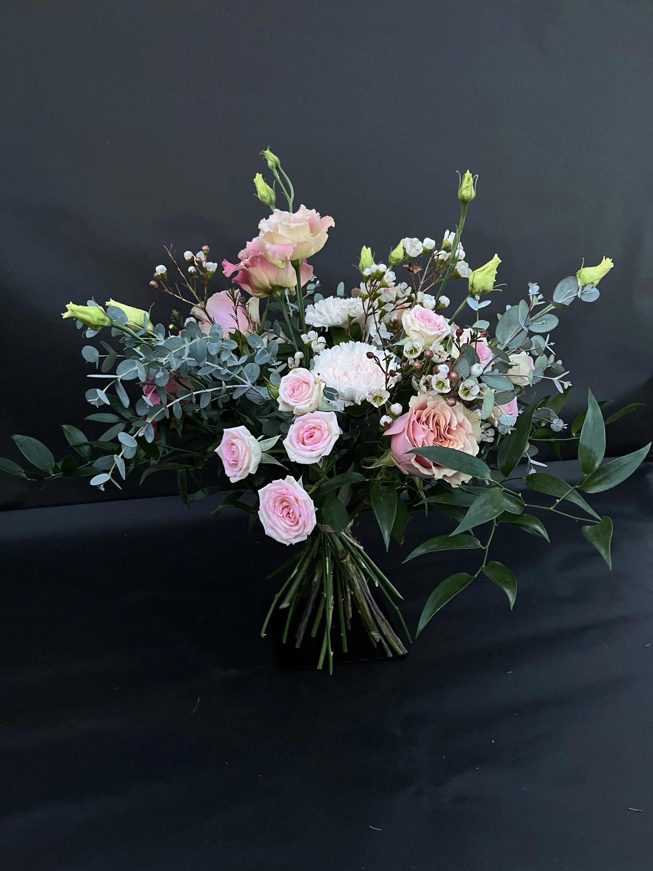 En bukett av rosa och vita blommor på en svart bakgrund.