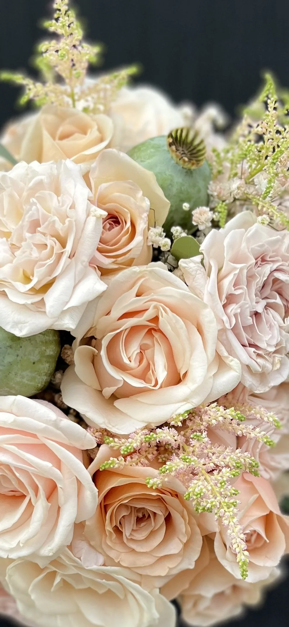 Blomsterarrangemang med rosa och vita rosor, gröna blad och små vita och rosa blommor.