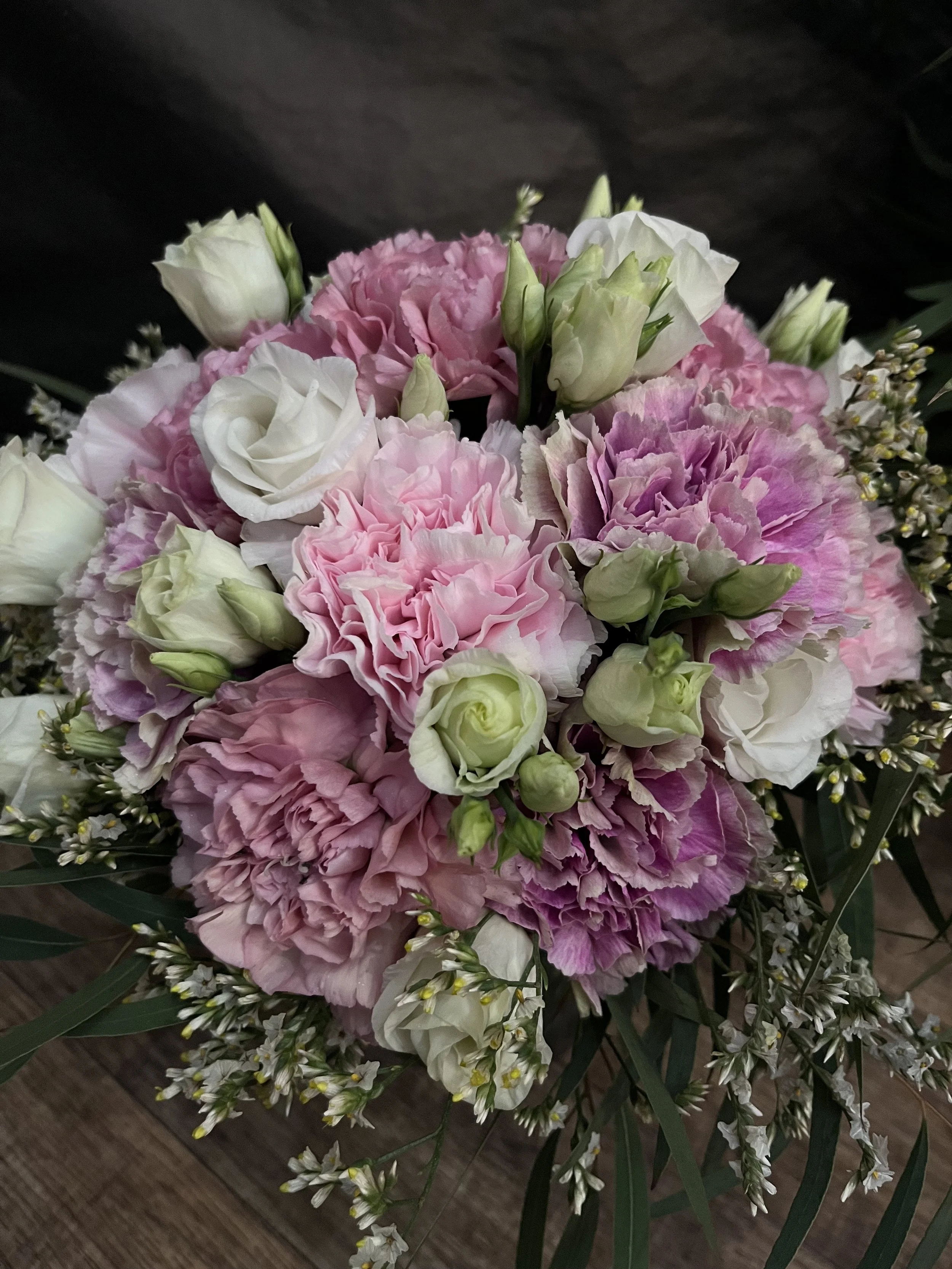 En bukett med rosa och vita blommor, inklusive rosor och nejlikor.