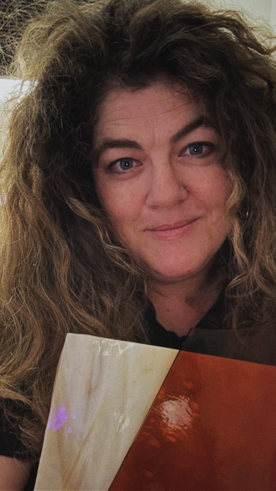 Een vrouw met lang, golvend bruin haar en lichte huid houdt glasplaat vast