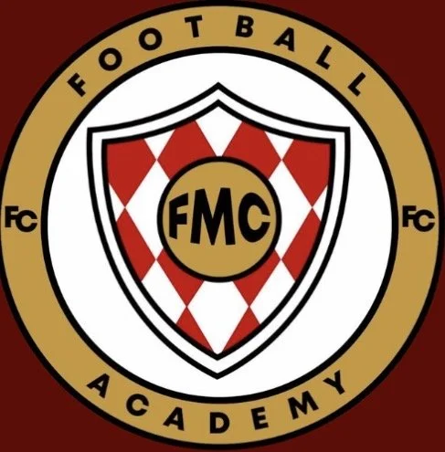 The logo of FMC Football Academy featuring a shield with a red and white diamond pattern and the initials 'FMC' inside a gold circle, surrounded by a gold ring with black text reading 'FOOTBALL ACADEMY' and 'Fc' on each side.