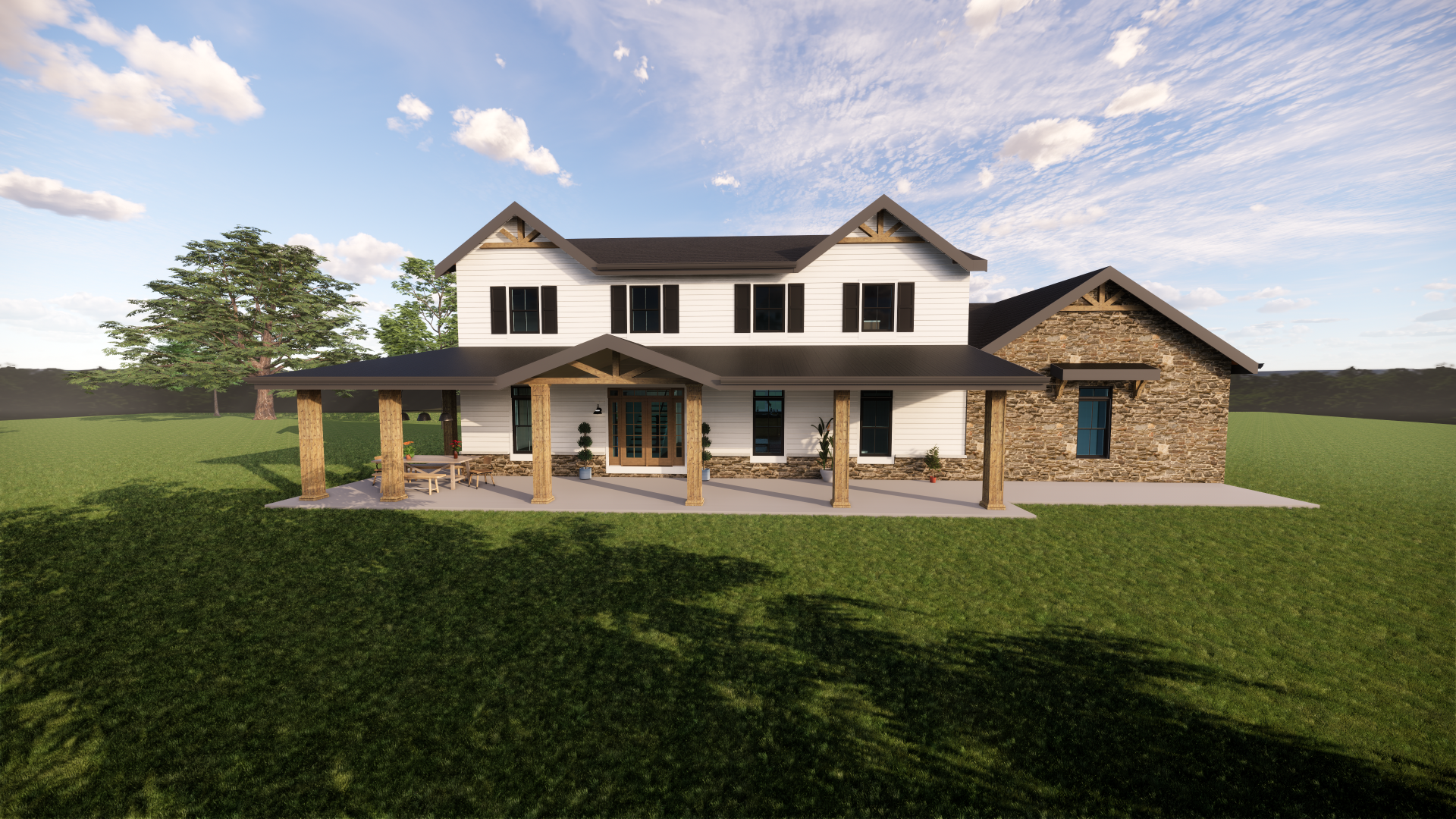 A large two-story house with white siding, black shutters, and stone accents. It has a covered porch with wooden columns, outdoor furniture, and potted plants. The house is set in a grassy landscape with a few trees and a cloudy sky.