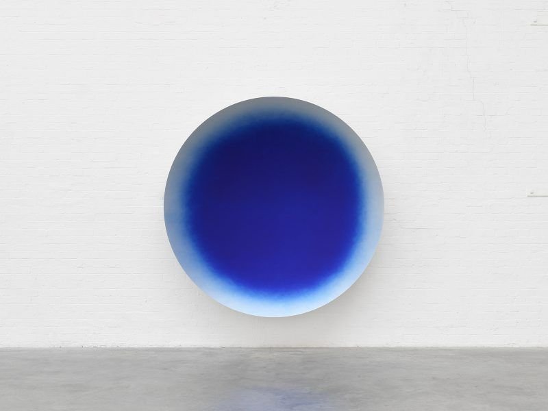 Blue circular artwork hanging on a white wall.