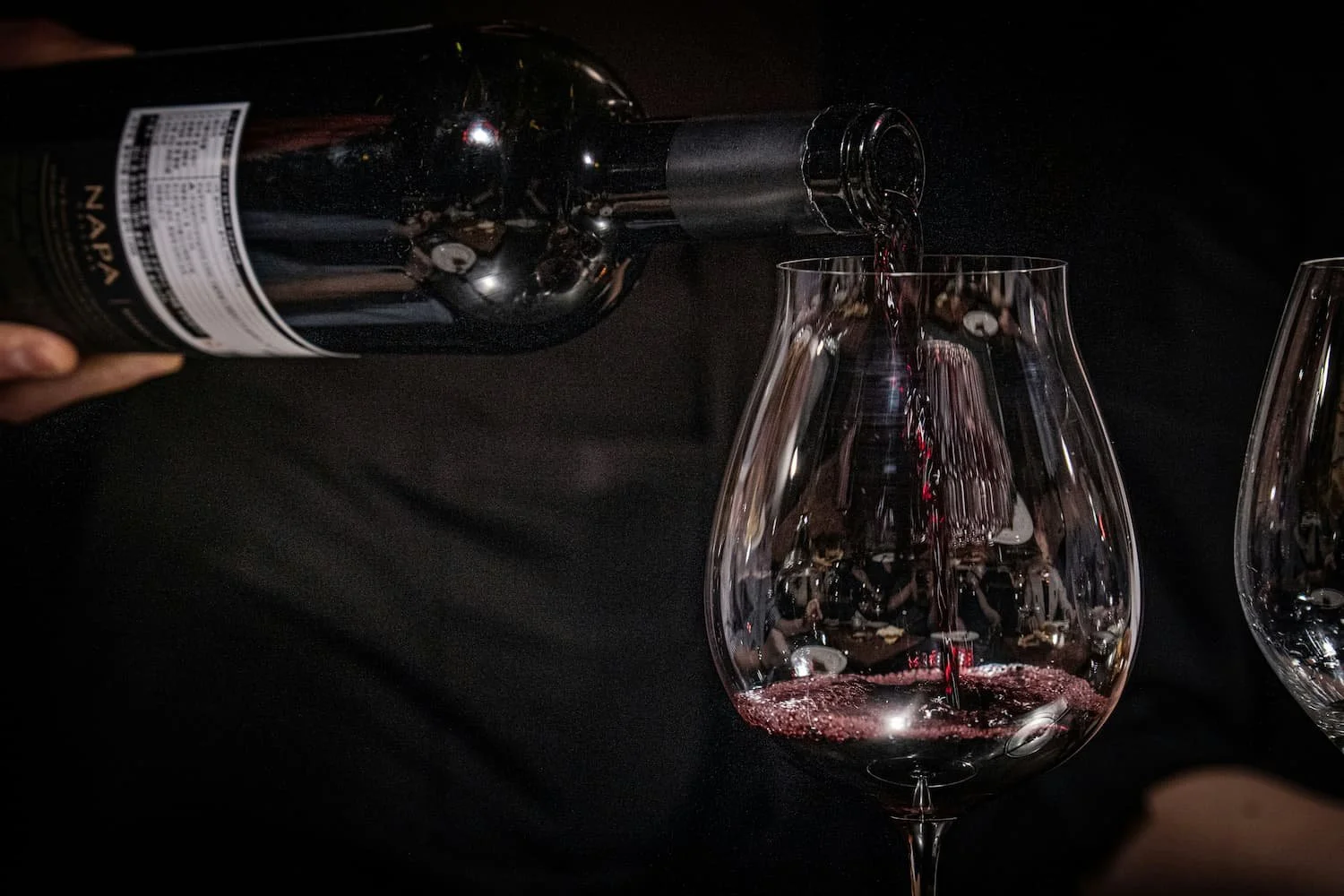 Red wine being poured in to two glasses