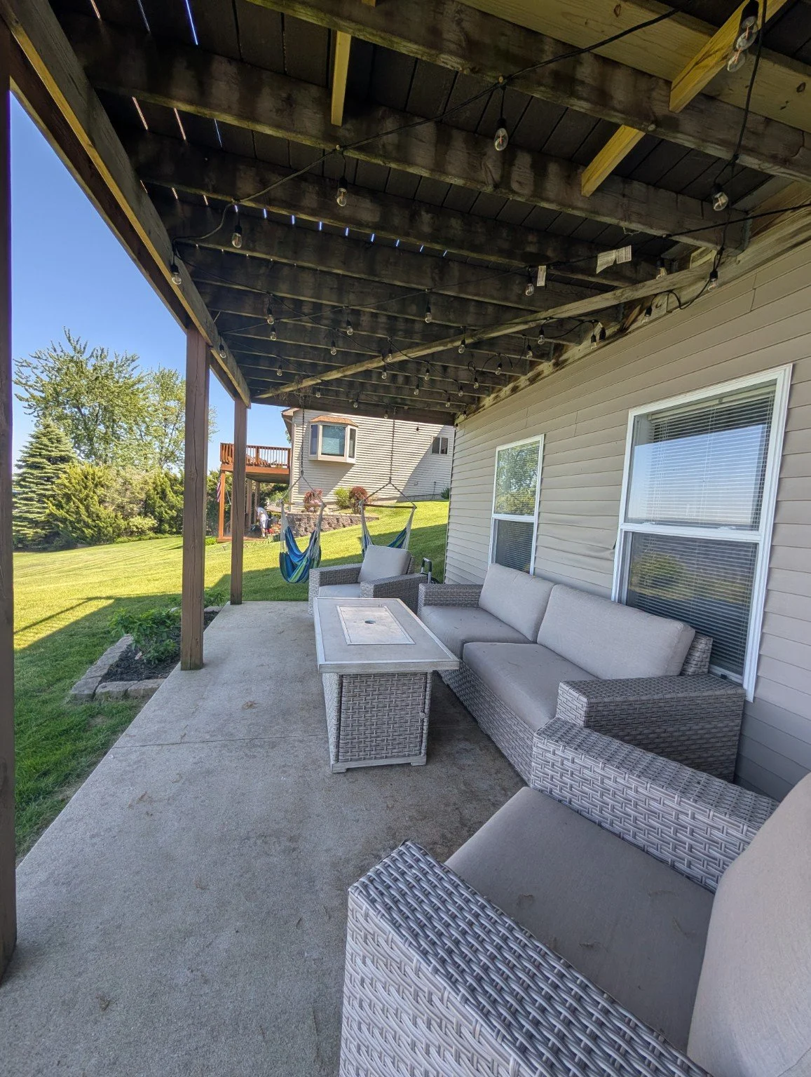 Covered patio with outdoor sofas and string lights at a Houghton Lake vacation rental