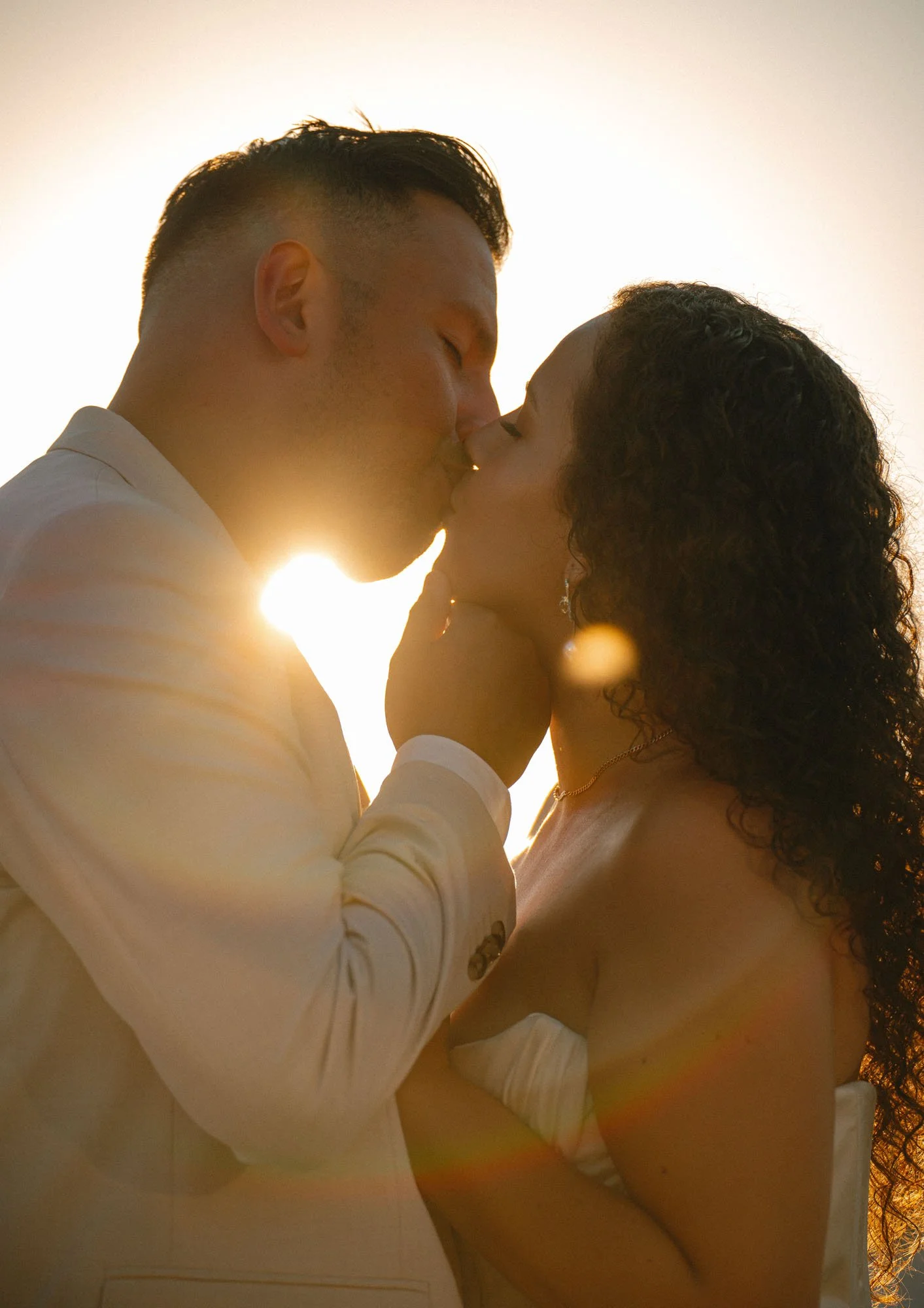 A couple kissing during sunset with sun rays and lens flare.