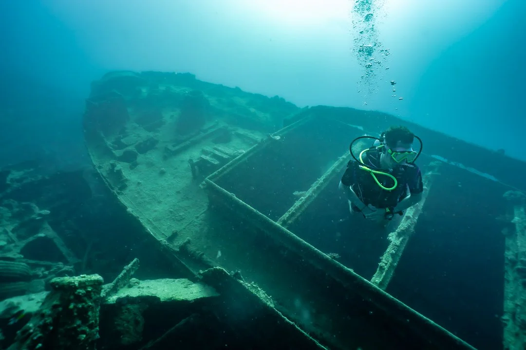 Scuba diver exploring the wreckage of a sunken ship underwater.