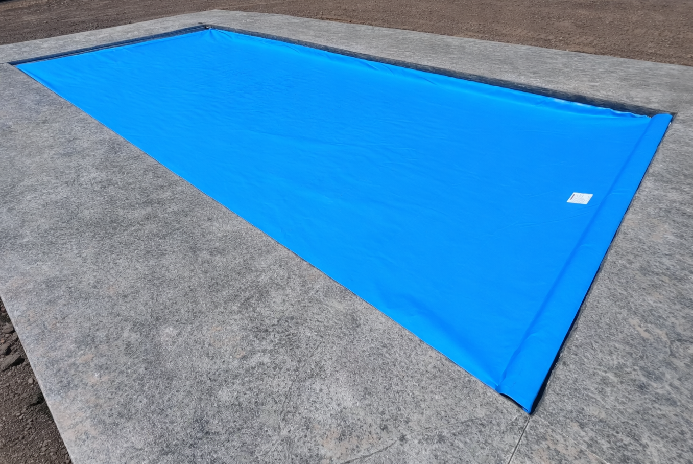 Inground pool covered by a blue, under guide automatic pool cover.