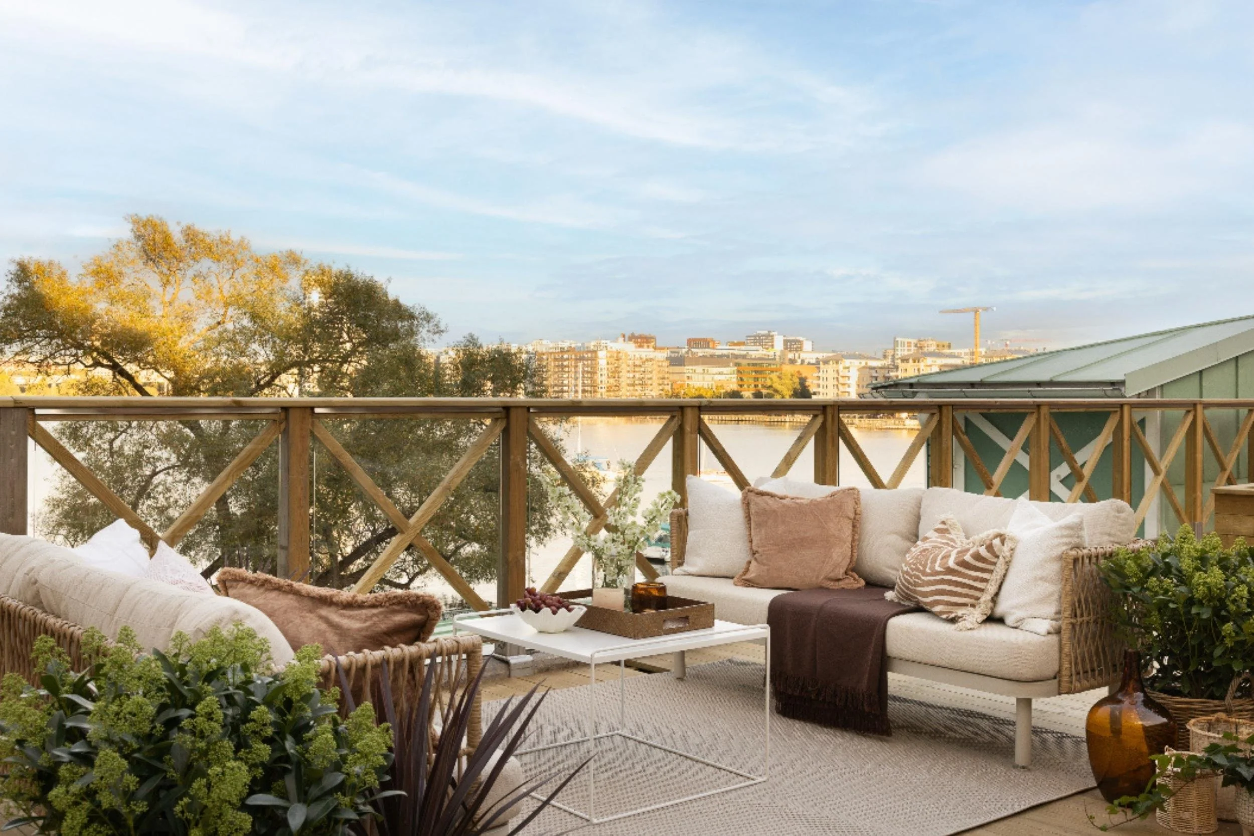 Uteplats med havsutsikt och vy över Kungsholmen i Stockholm, stylad med soffor, bord, textilier, detaljer och grönska