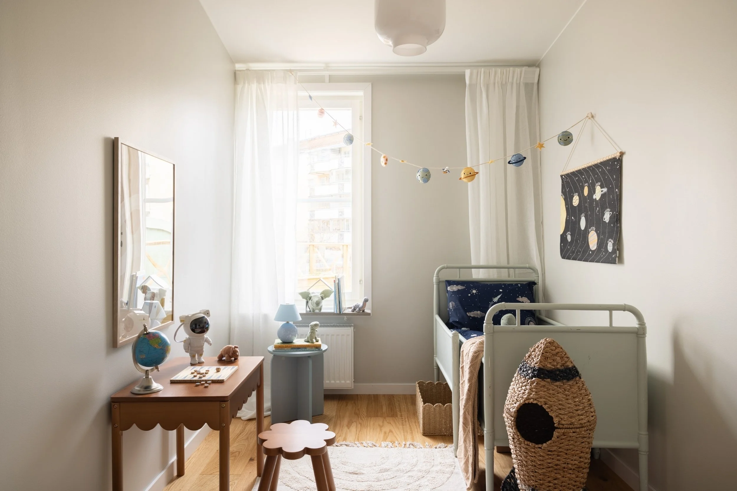 Ombonat barnrum stylat med säng, sängbord, skrivbord och pall samt detaljer som tavlor och dekor med rymdtema