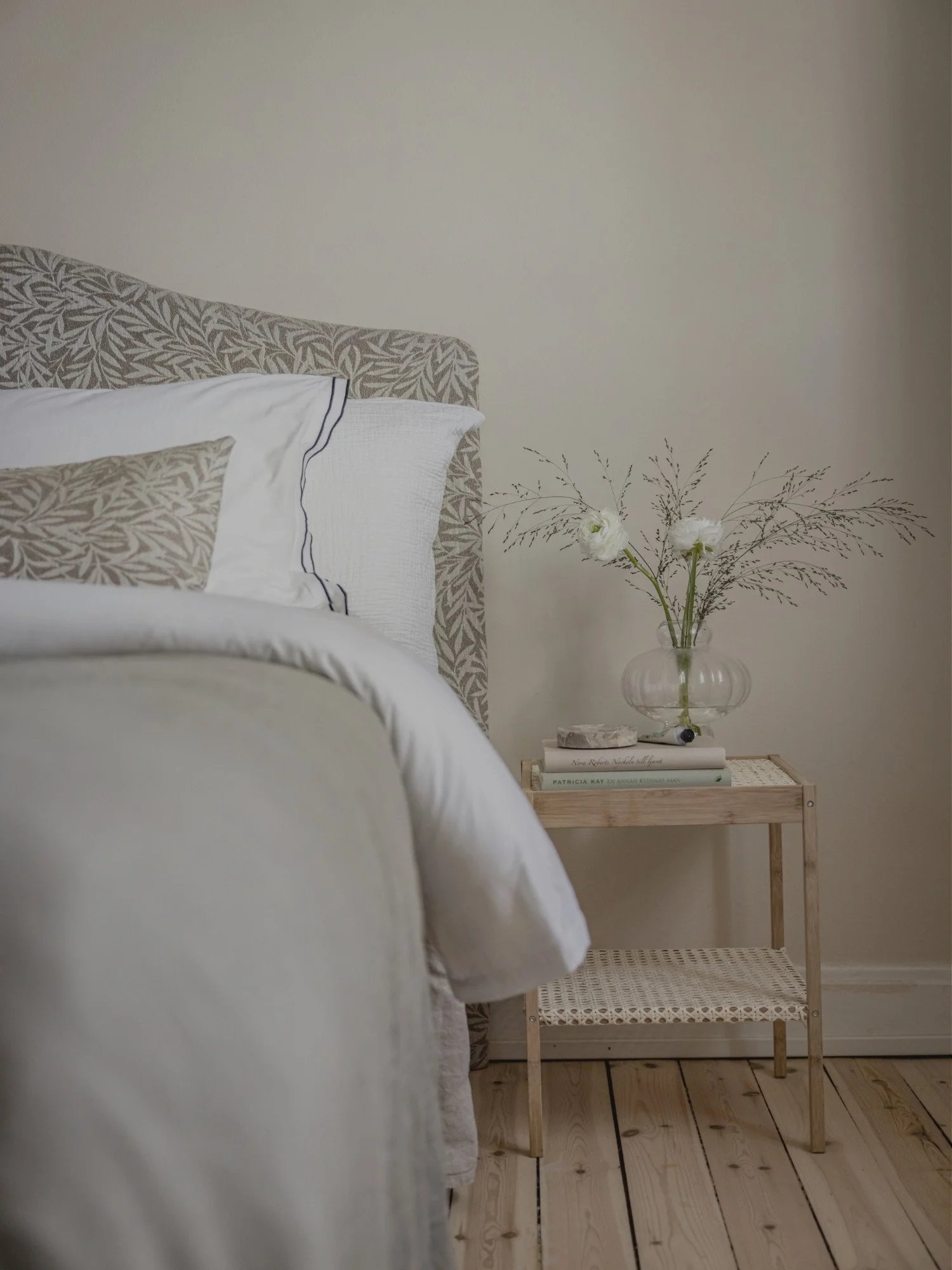 Styling av sovrum med mjuka textilier, sänggavel, inredningsdetaljer och blommor