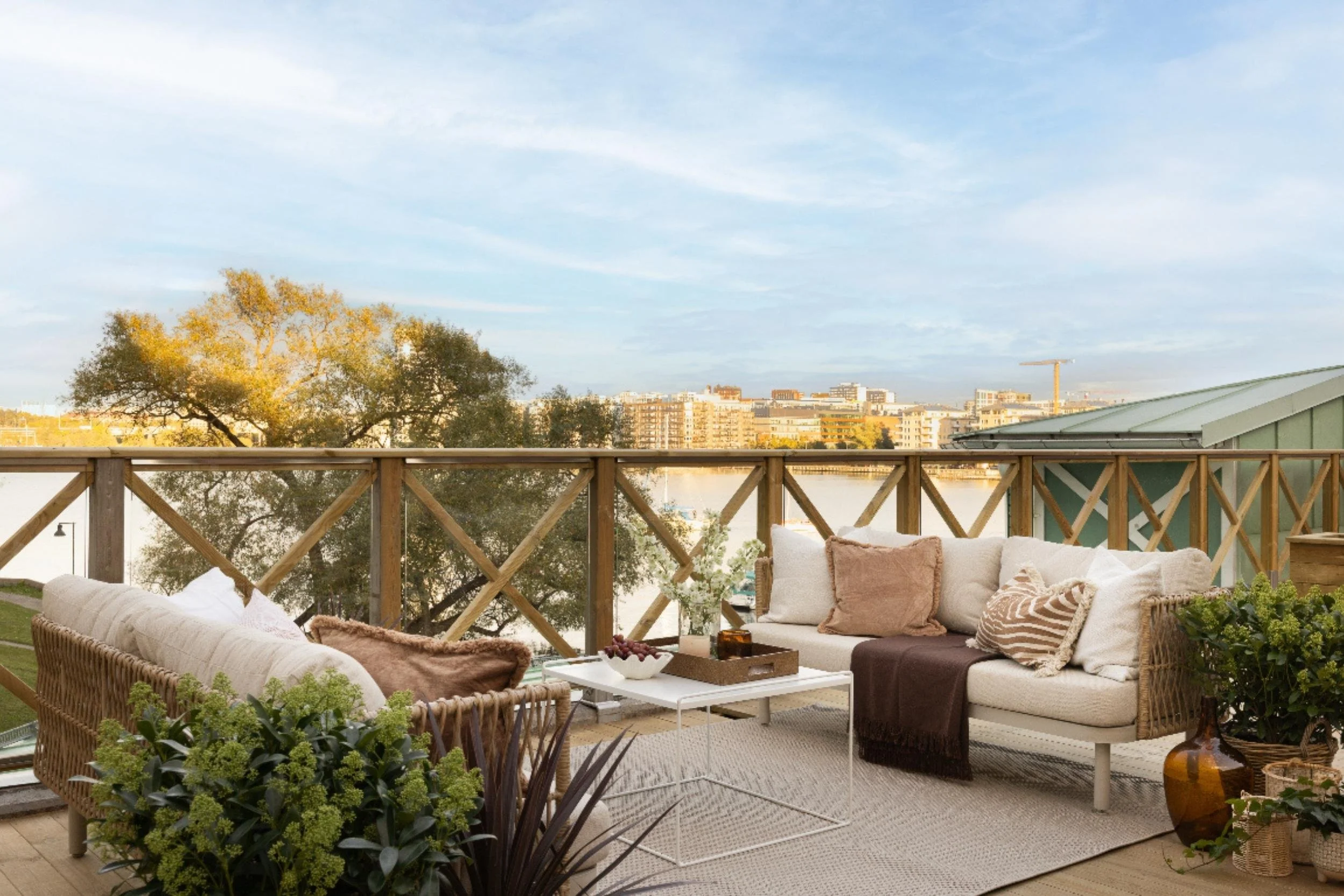 Ombonad terrass med havsutsikt inredd med soffor, brickbord, växter och textilier i dämpade färger