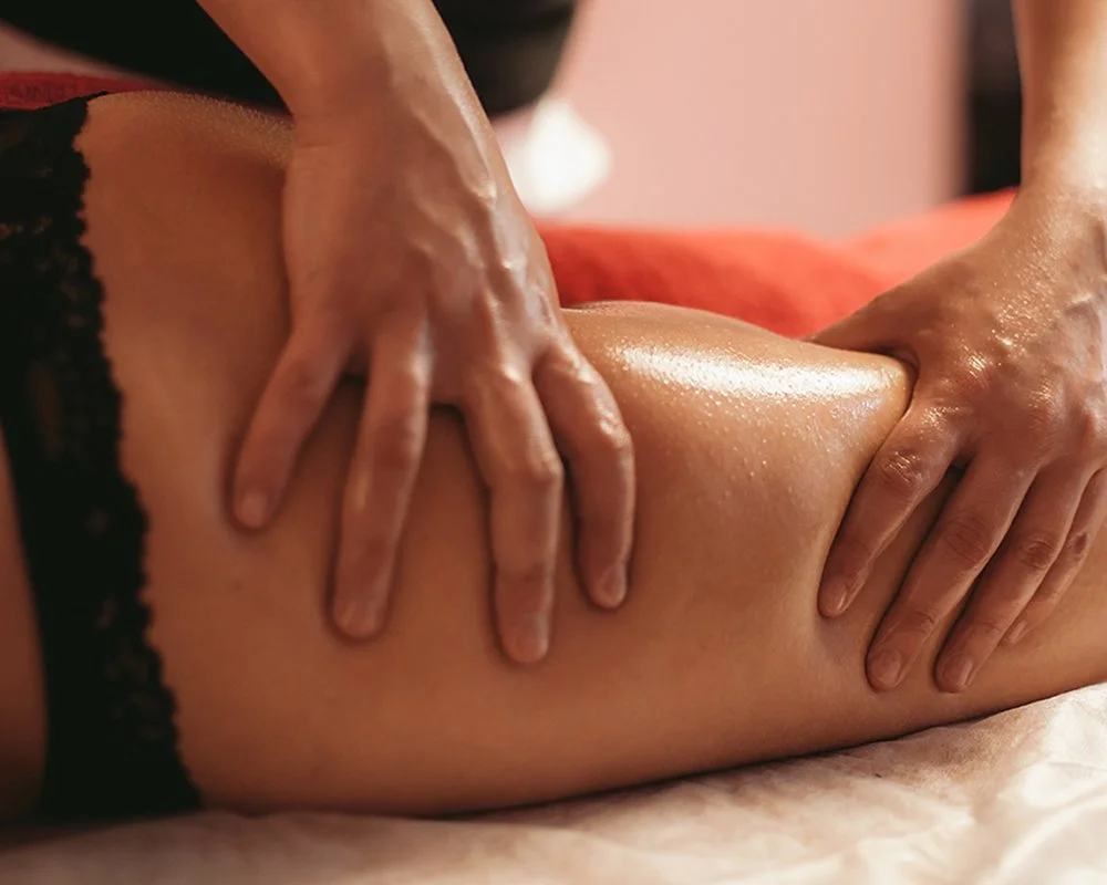 Close-up of a massage therapist's hands massaging a person's leg at Renewed Life Esthetics and Head Spa.