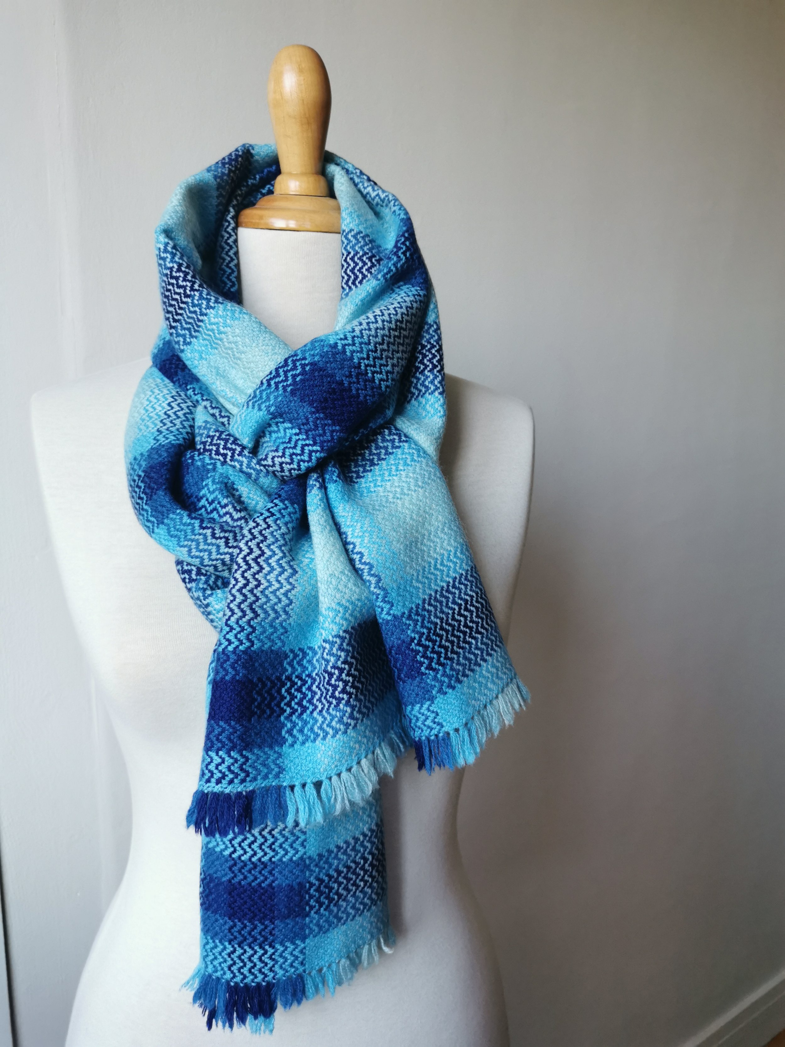 Écharpe Source en pur cachemire nouée autour du cou d'un mannequin, motif de carreaux en nuances de bleu et turquoise, courtes franges libres en bas