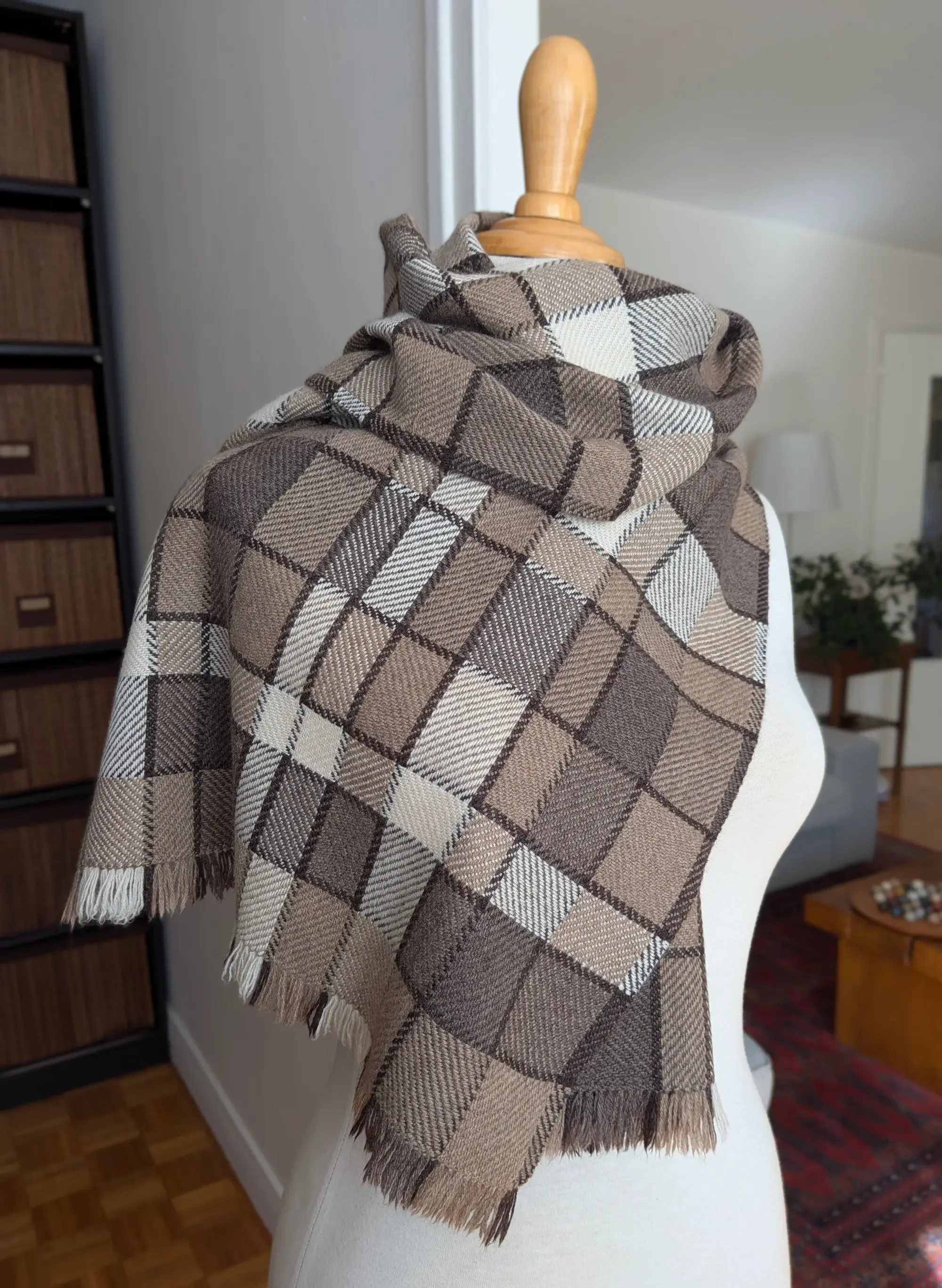 Écharpe Agate en pur cachemire enroulée autour du cou d’un mannequin, carreaux taupe, bruns et blanc cassé, franges beiges et brunes en bas