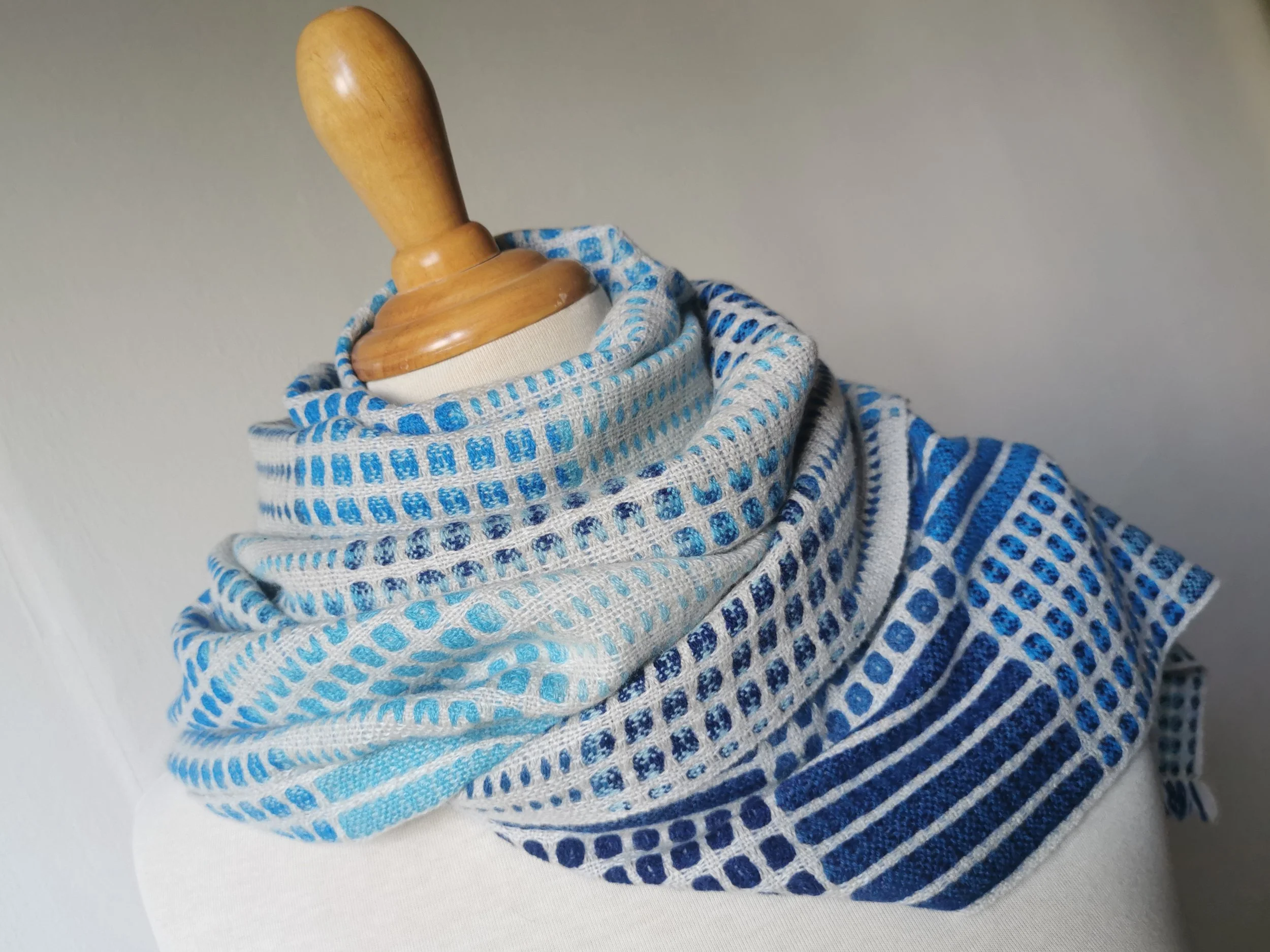 Écharpe Variation en bleu enroulée autour du cou d'un mannequin, vue de côté : une face claire à pois bleus et une face bleu marine à rayures, visibles ensemble