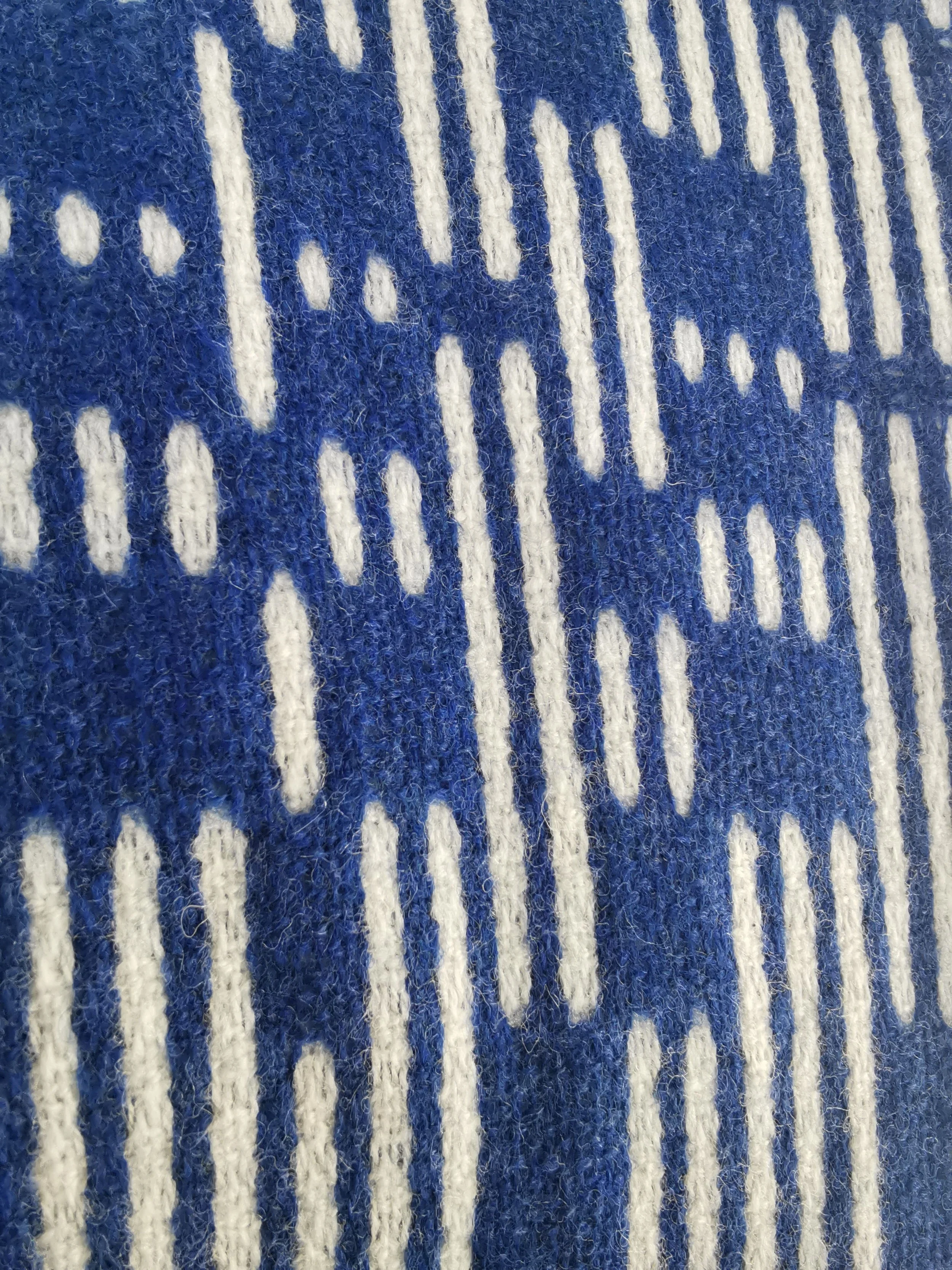 Gros plan sur la face bleu cobalt de l'écharpe Sillage : tirets écrus de longueurs variées, léger duvet de la laine mérinos