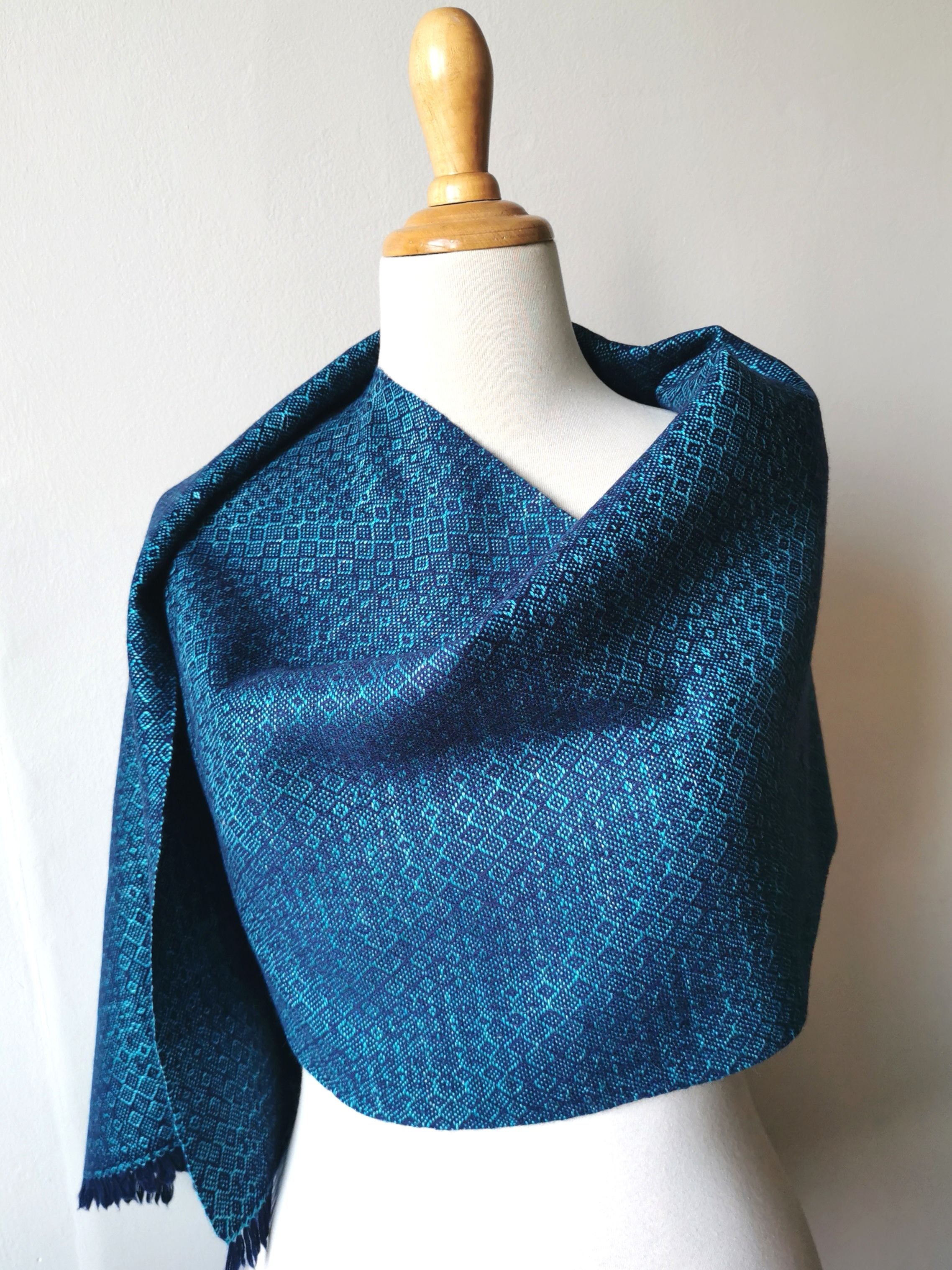Étole Ondine en cachemire et soie drapée sur les épaules d'un mannequin, motif en losanges dans un camaïeu de bleu marine et turquoise
