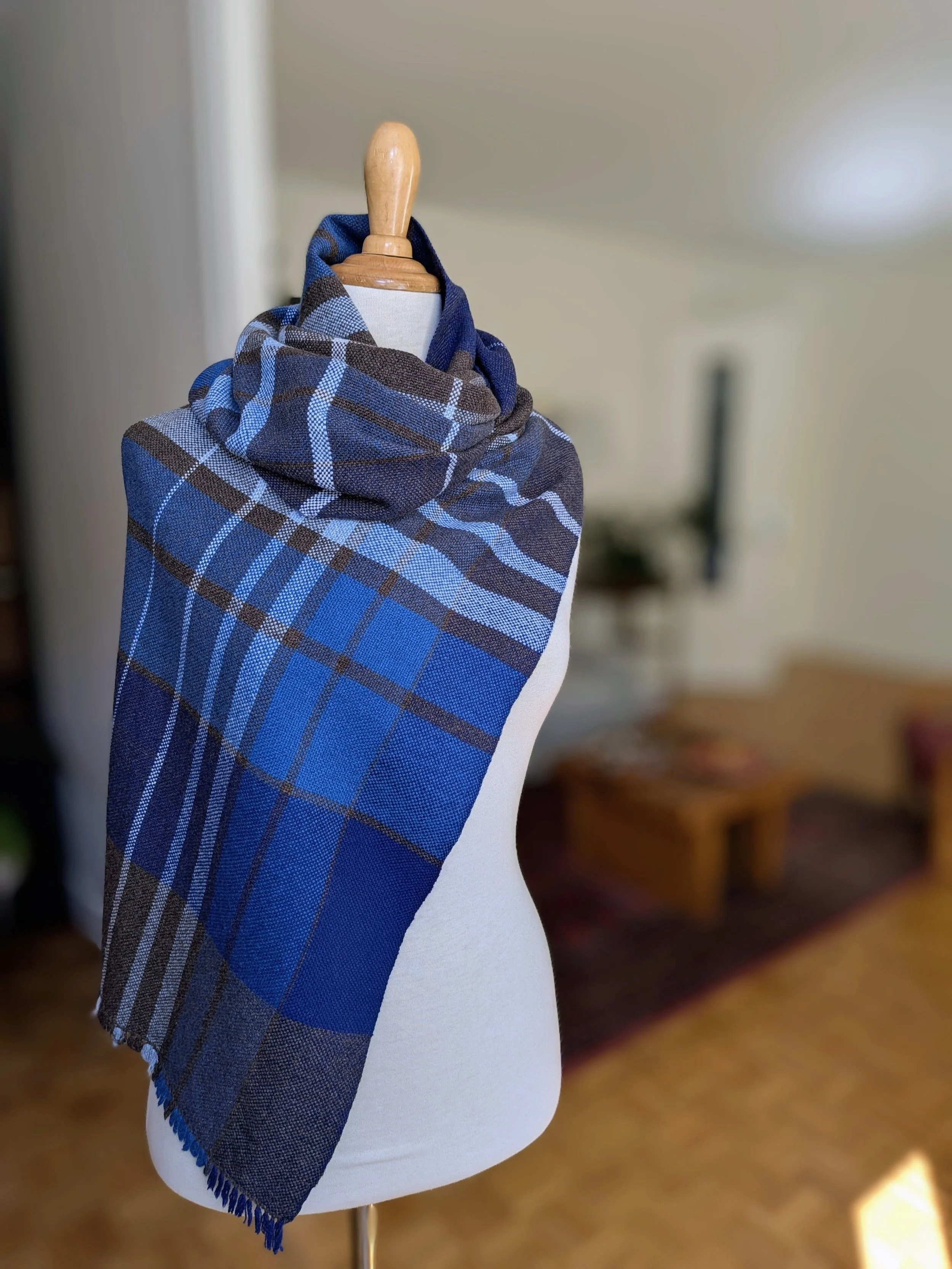 Écharpe Boréal en pur cachemire enroulée autour du cou d'un mannequin, motif de carreaux en camaïeu de bleus, brun profond et blanc, courtes franges libres en bas