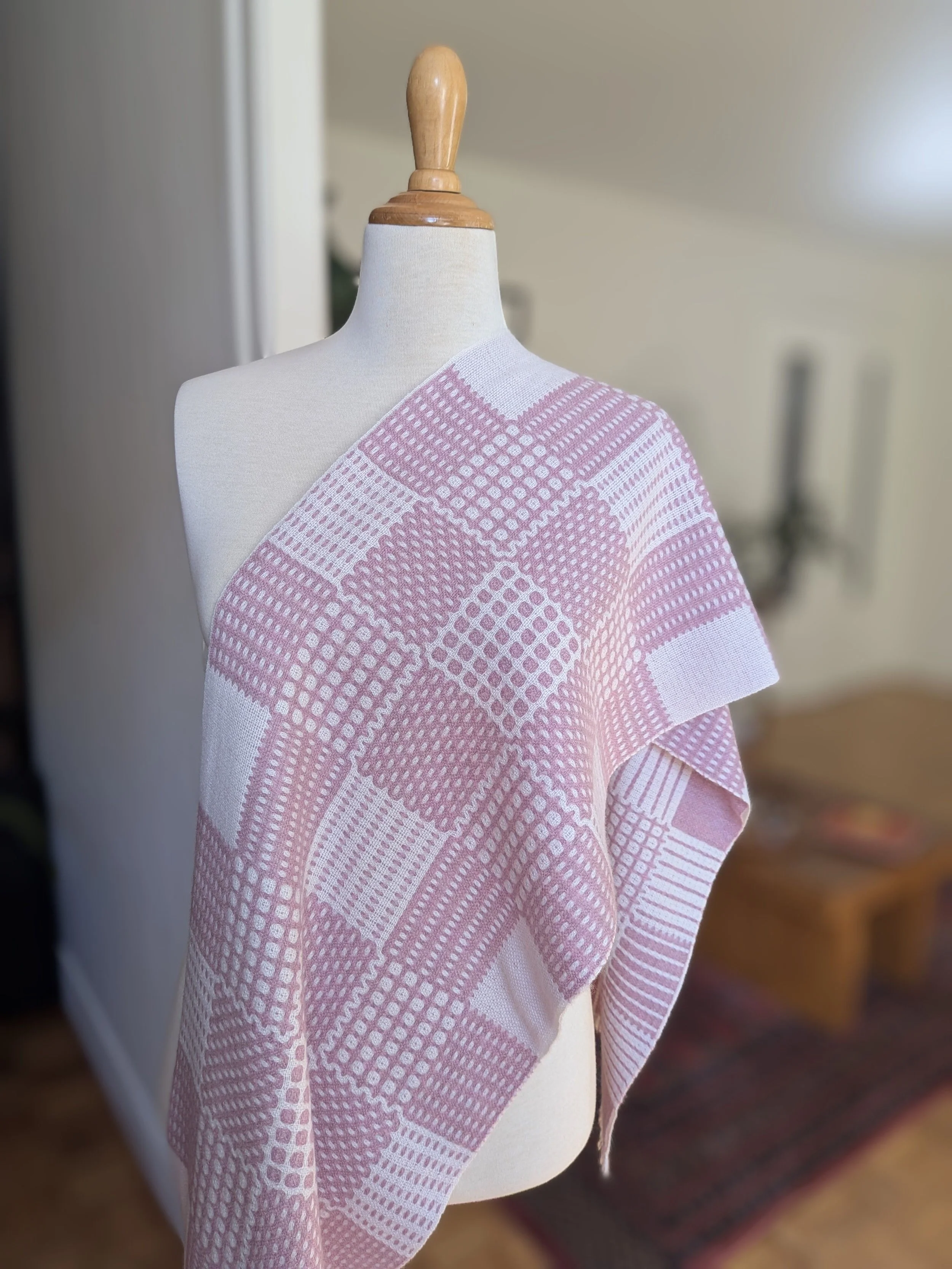 Gros plan sur l'écharpe Variation poudrée en pur cachemire drapée sur l'épaule d'un mannequin : motif de pois et de carreaux en rose chiné et blanc