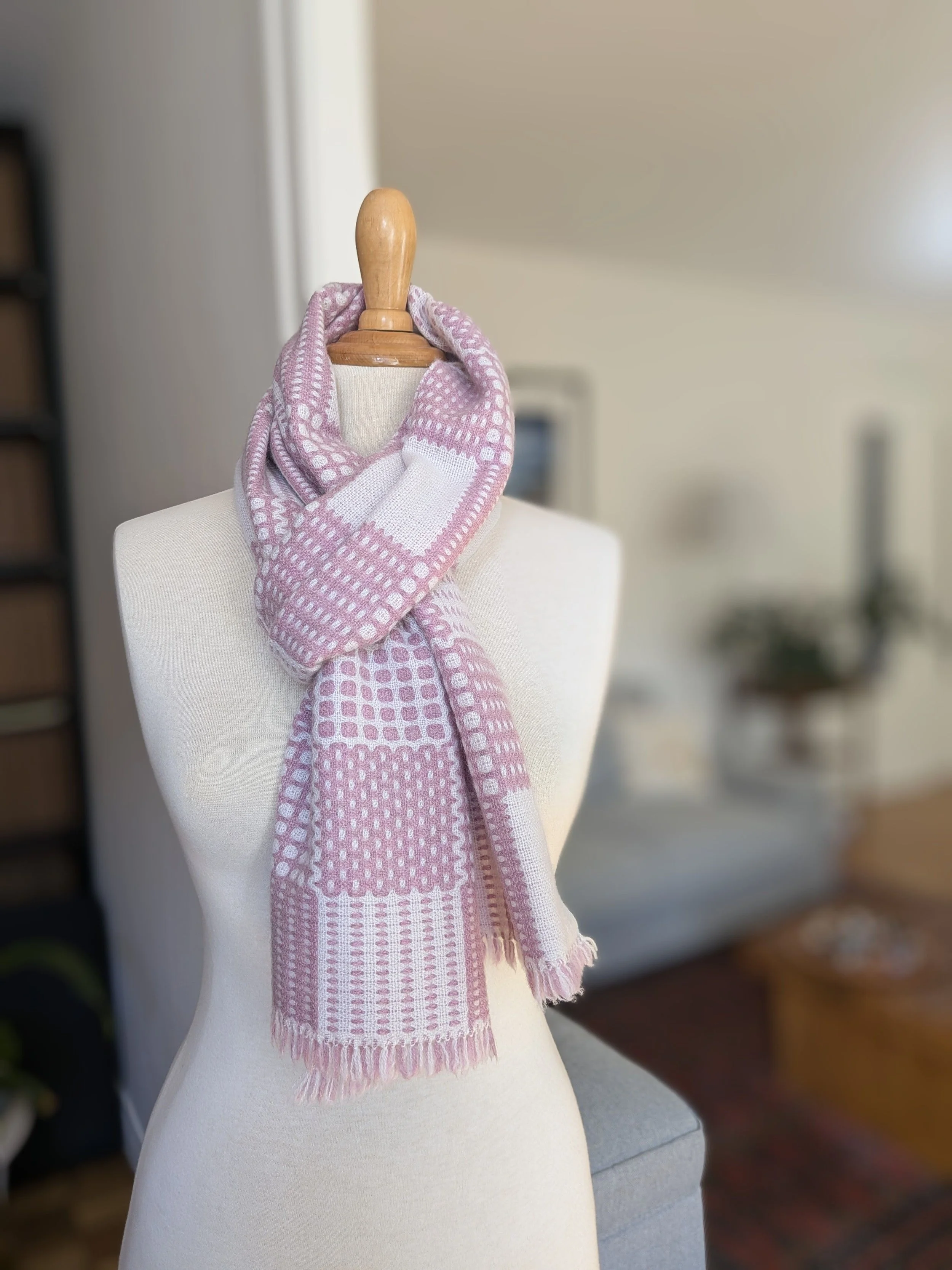 Écharpe Variation poudrée en pur cachemire nouée et croisée autour du cou d'un mannequin : motif de carreaux, pois et rayures en rose chiné et blanc, franges visibles
